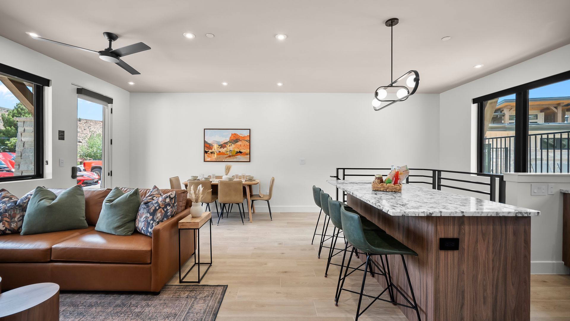 Open-concept living space with kitchen island, dining table, and brown leather sofa.