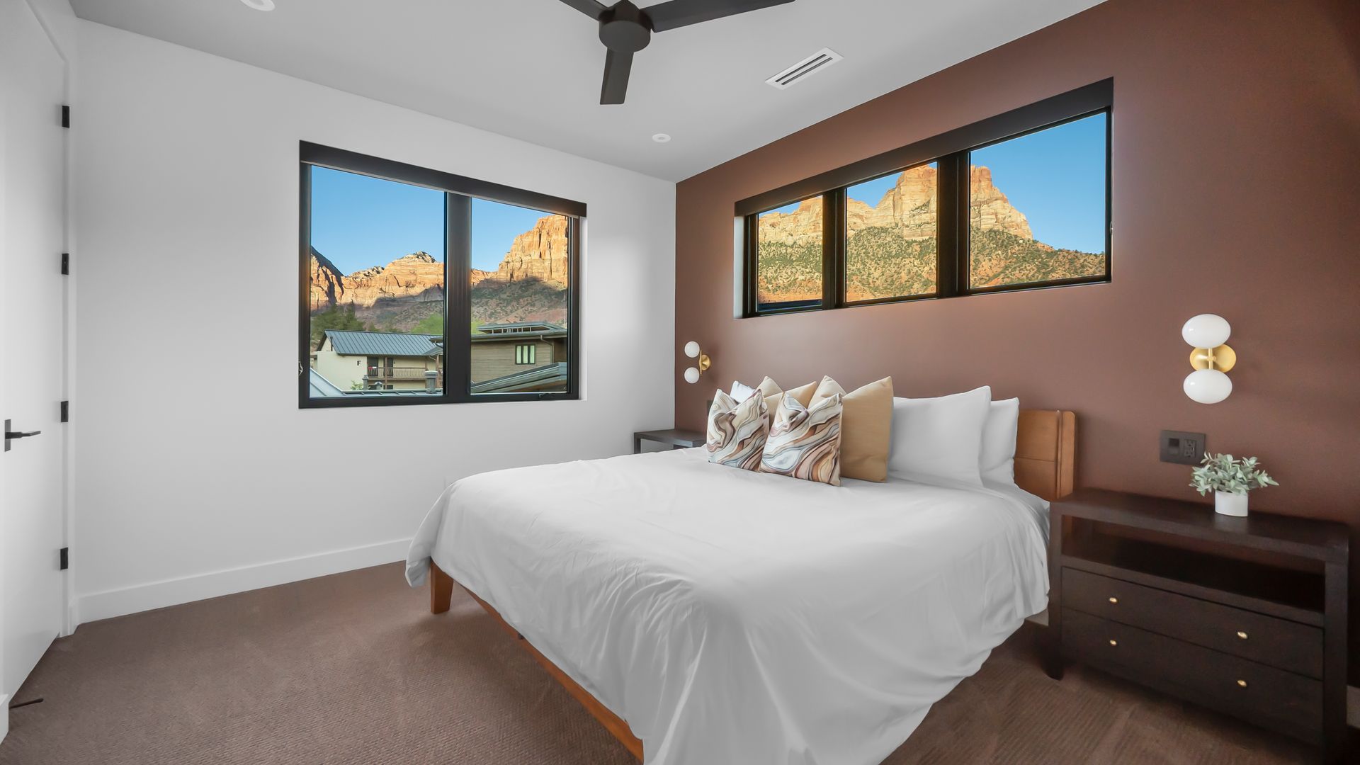 Bedroom with a bed, windows overlooking a mountain view, and a dark brown accent wall.