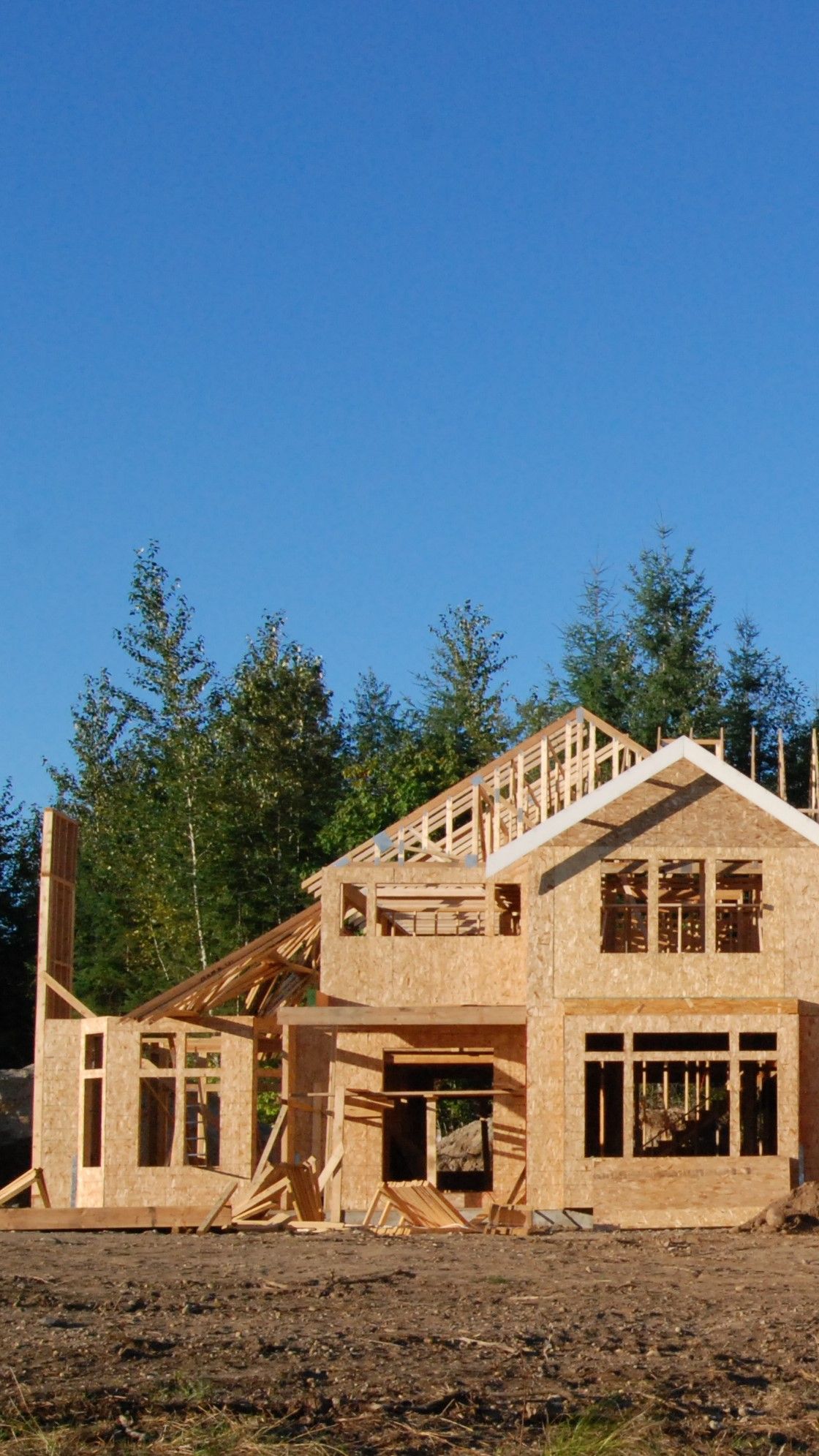 A large wooden house is being built in a field.