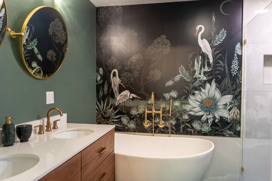 A bathroom with two sinks , a bathtub , a mirror and a mural on the wall.