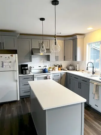 A kitchen with a large island in the middle and a refrigerator.