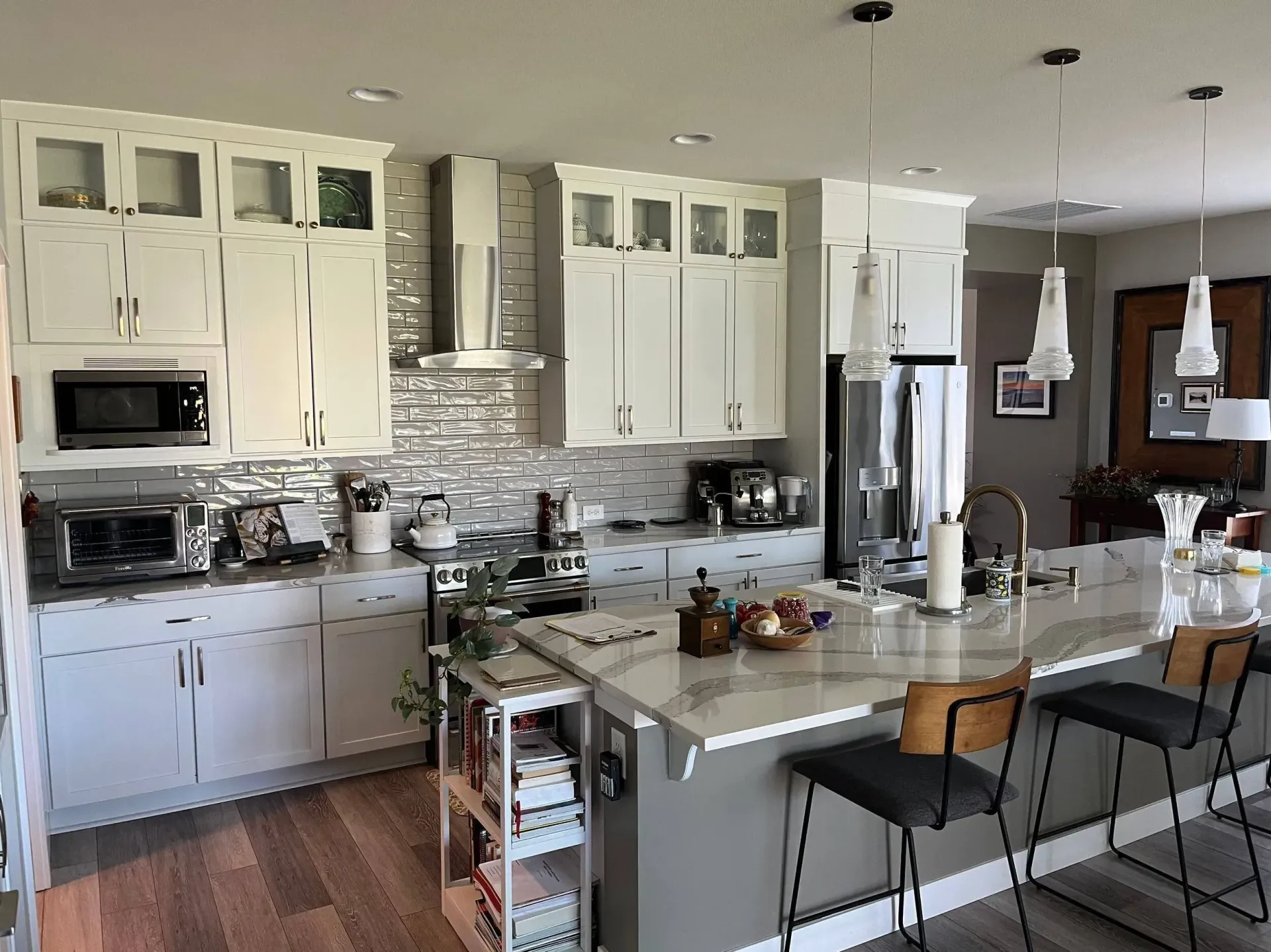 A kitchen with white cabinets , a large island , and stools.