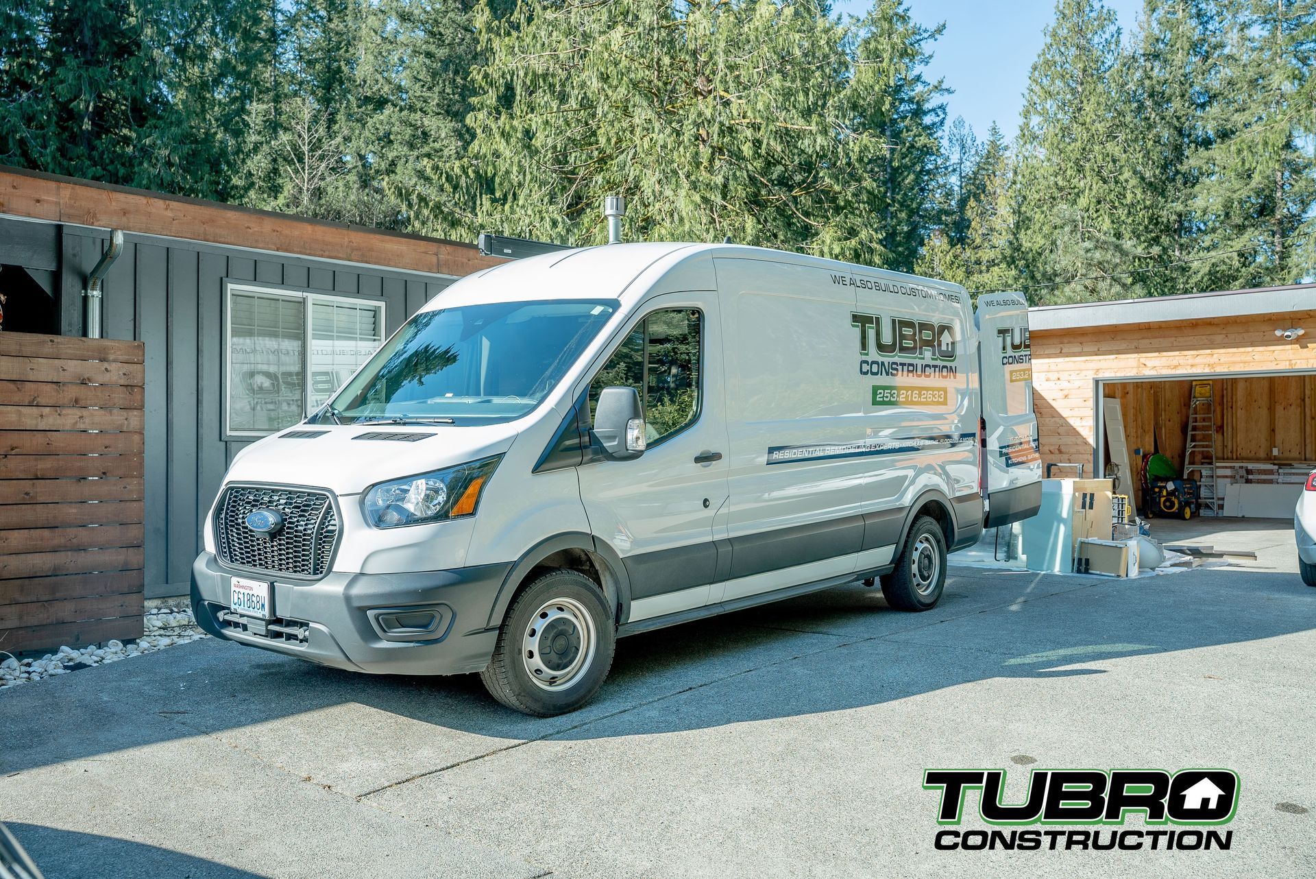 A white van is parked in front of a garage.