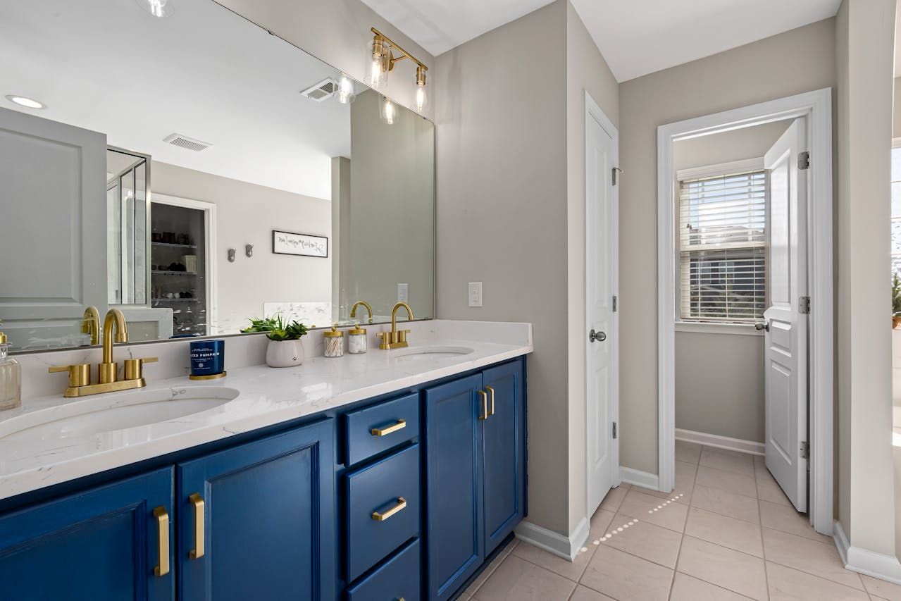 A bathroom with two sinks , a mirror , and blue cabinets.