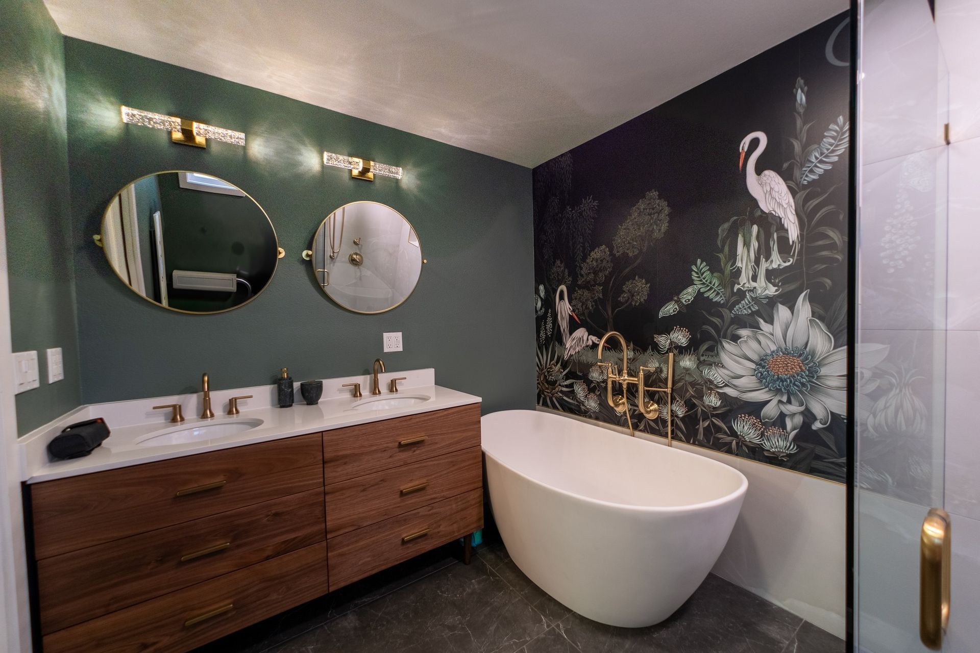 A bathroom with a bathtub , sink , mirrors and a mural on the wall.