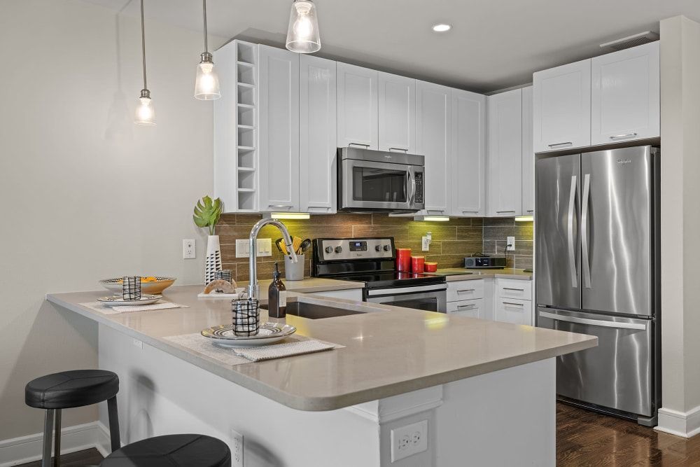 A kitchen with white cabinets , stainless steel appliances , a sink , and a refrigerator at Water's Edge.