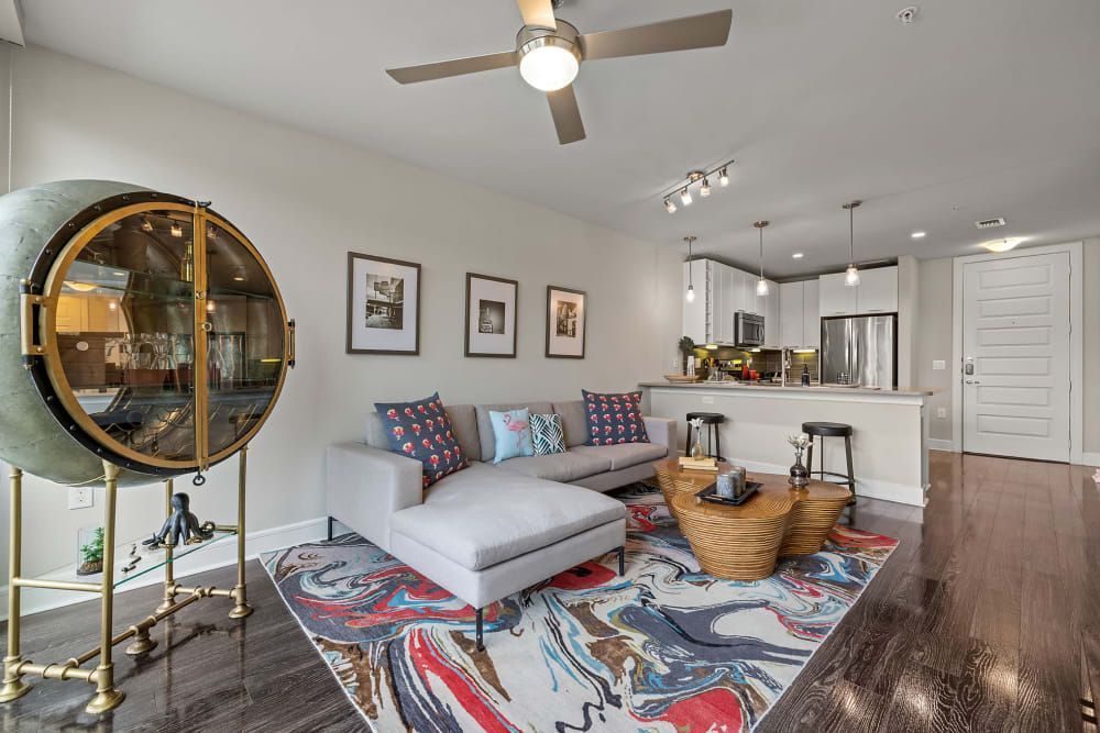 A living room with a couch , coffee table , rug and ceiling fan at Water's Edge.