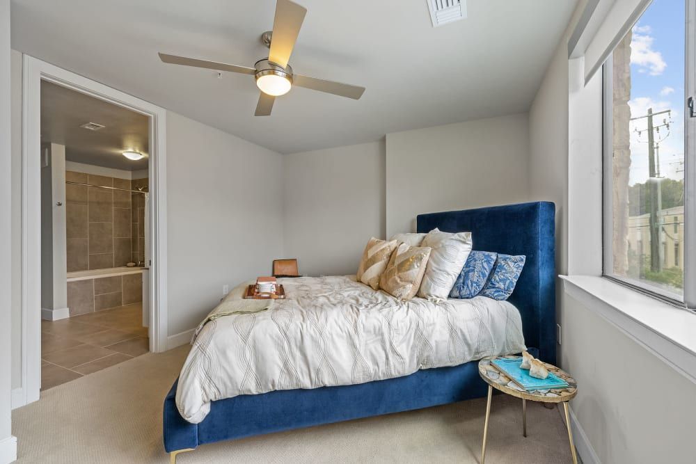 A bedroom with a bed , ceiling fan , and window at Water's Edge.