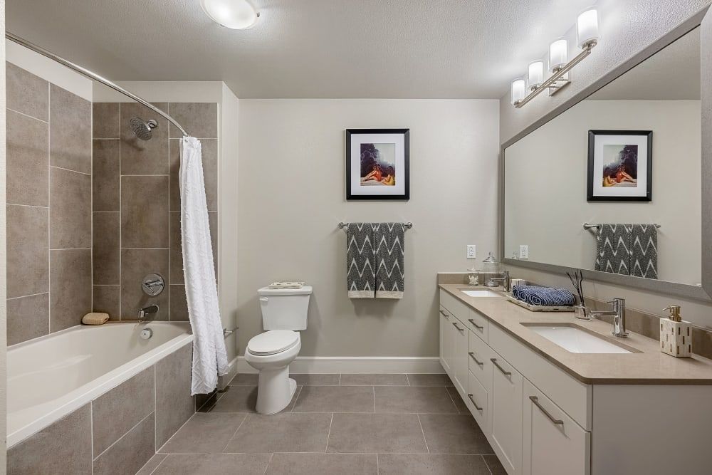 A bathroom with a toilet , sink , tub and mirror at Water's Edge.