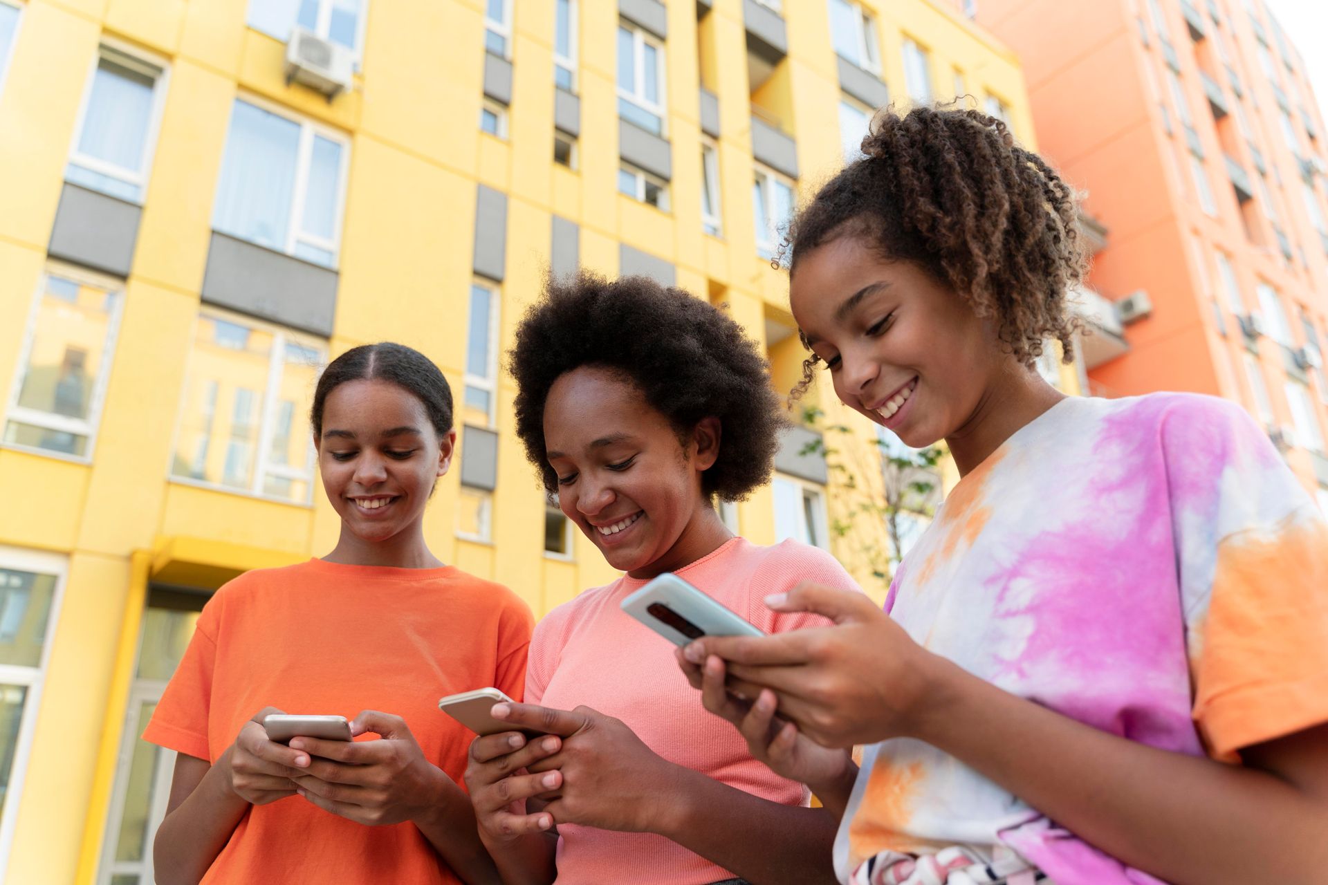 a woman and her daughters smiling and using phones