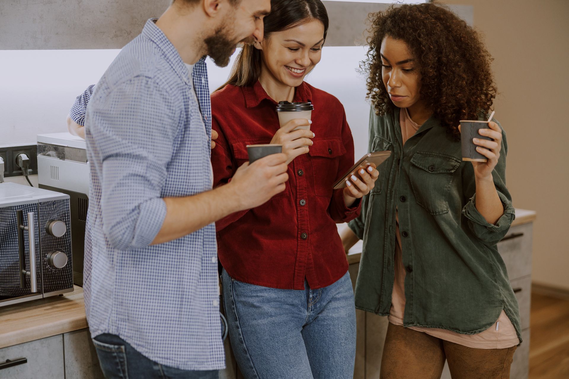 three people in office with mobile phone