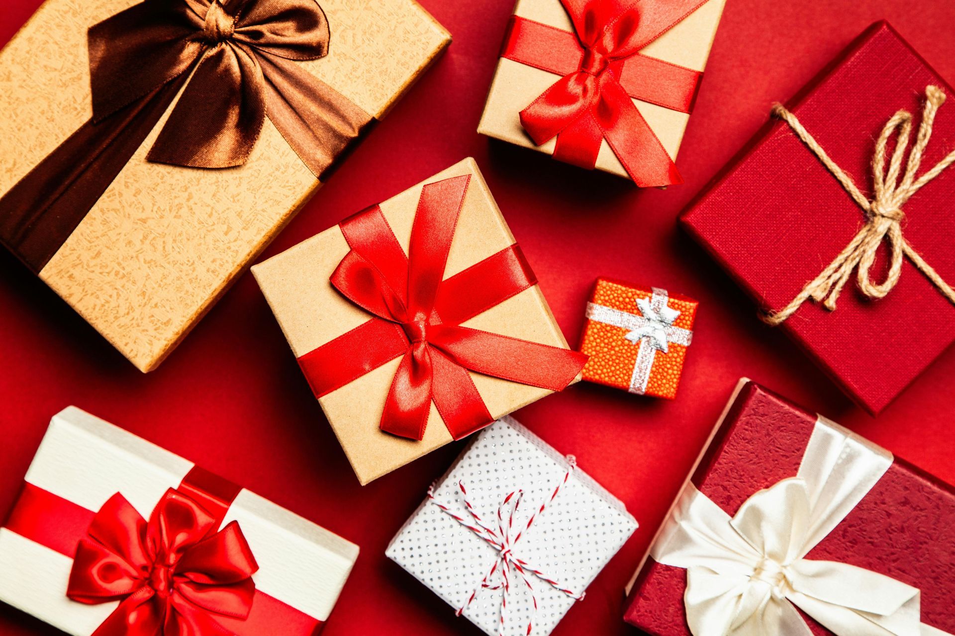 A group of gift boxes with red ribbons and bows on a red surface.
