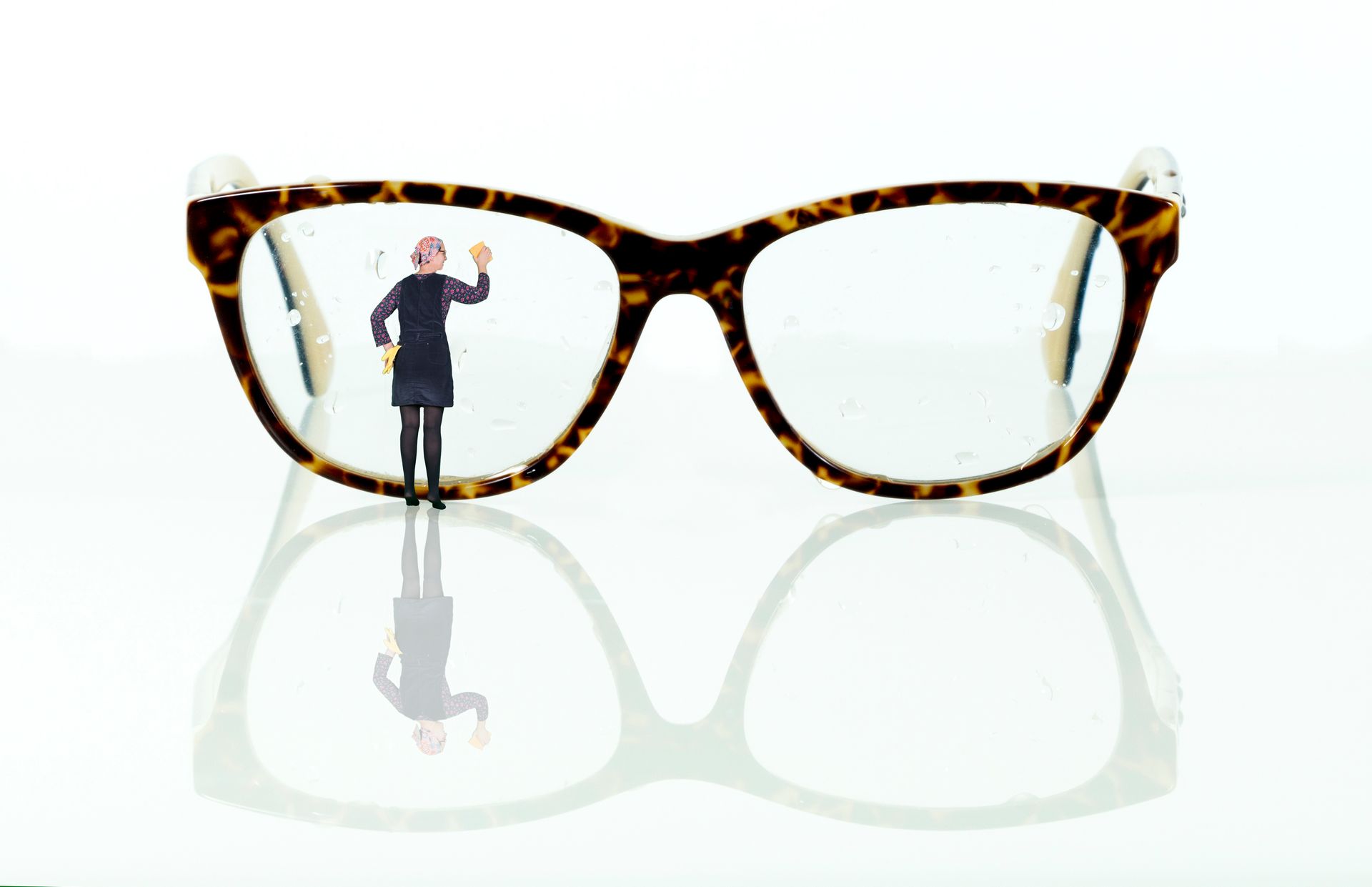Een klein beeldje staat op het montuur van een bril met luipaardprint en lijkt het oppervlak van de lens schoon te maken.