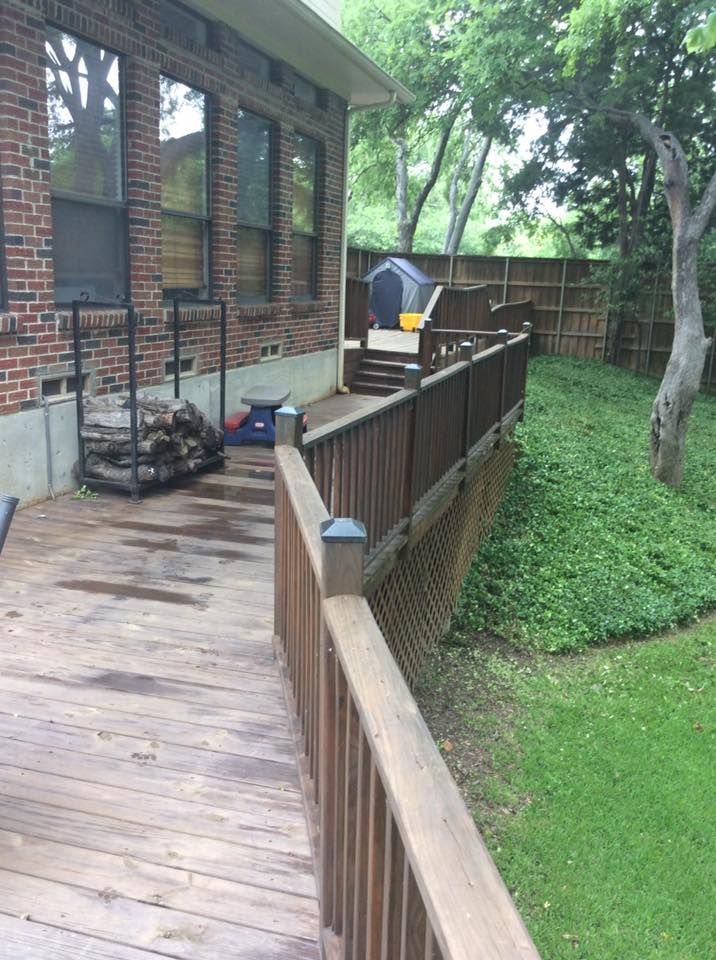 A wooden deck with a brick house in the background