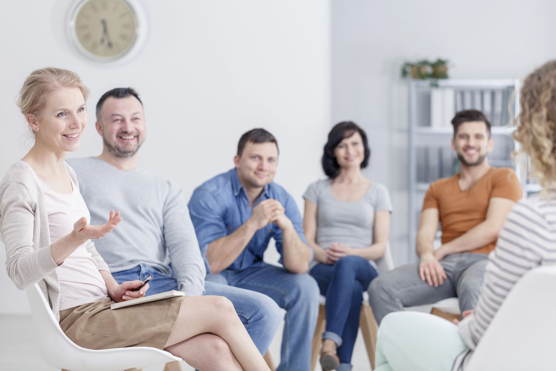 Small group in a bright room, seated in a circle and talking during a discussion session.