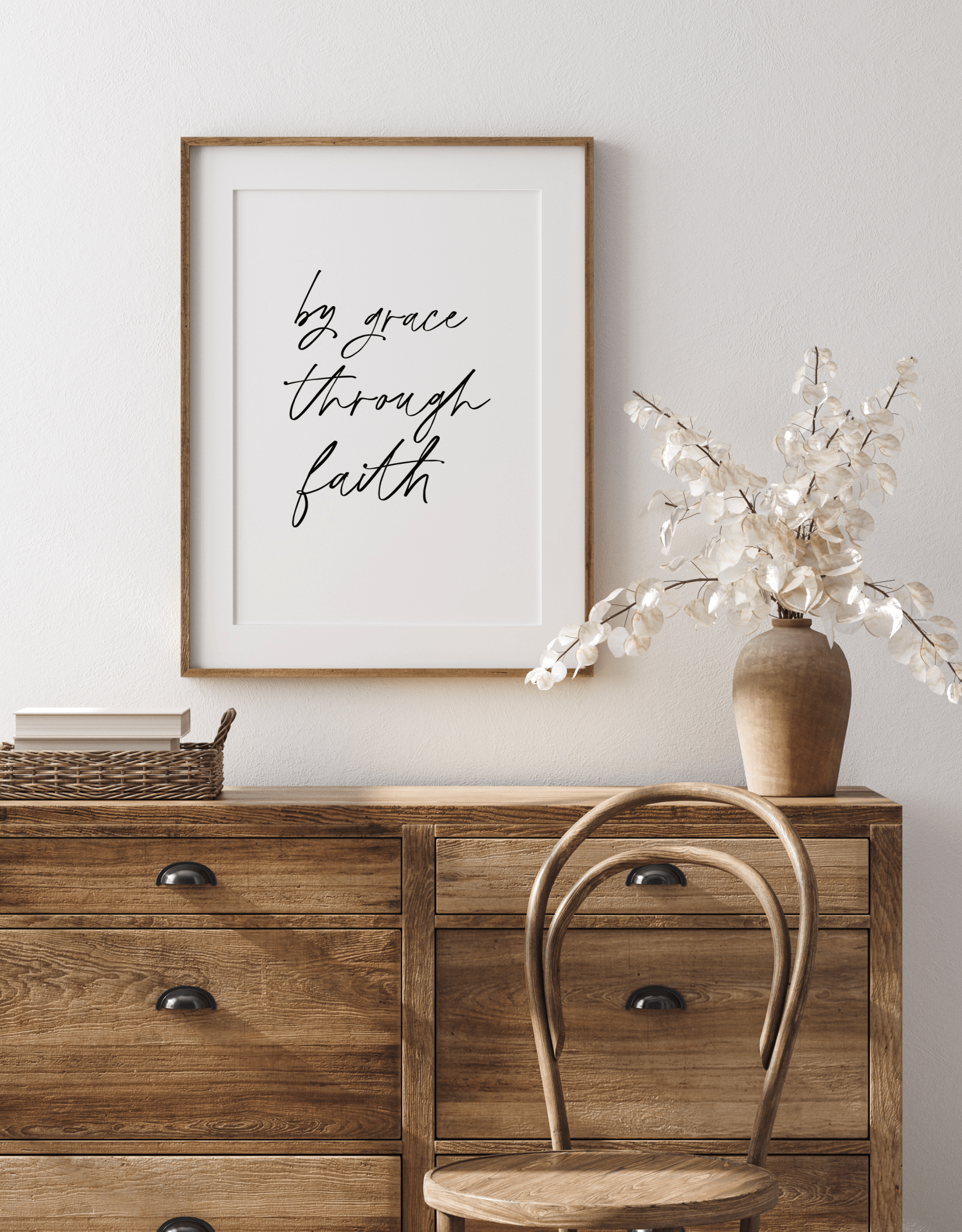 wooden desk with sign above that say by grace through faith that you can buy in their store. White flowers and basket on desk with wooden chair in front.