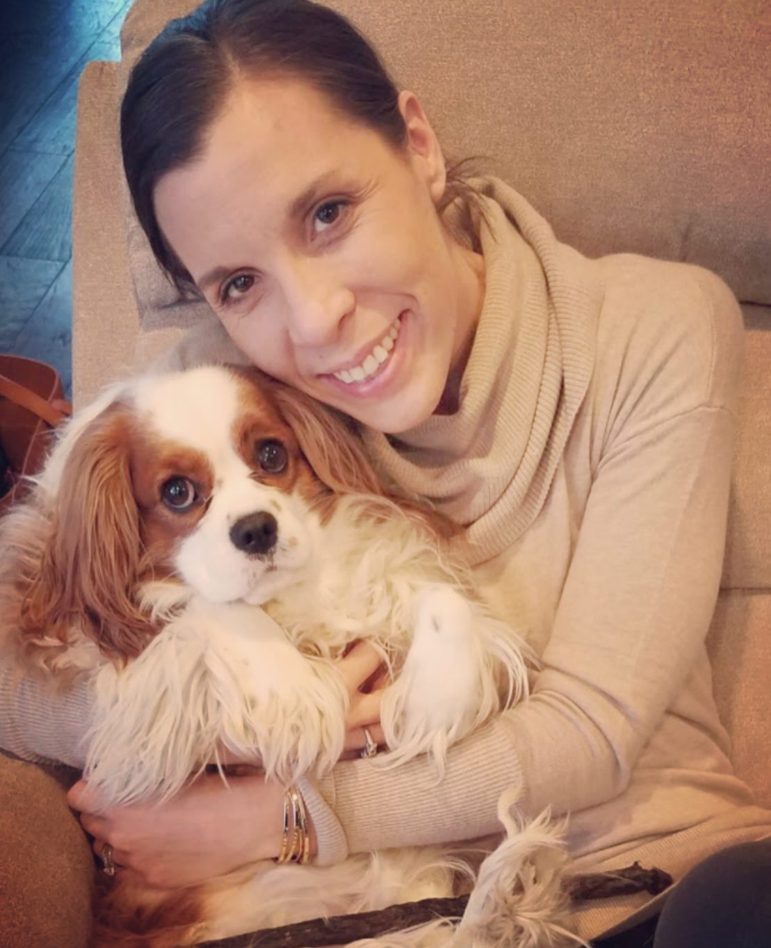 amy sitting in recliner with cavalier king Charles spaniel  smiling
