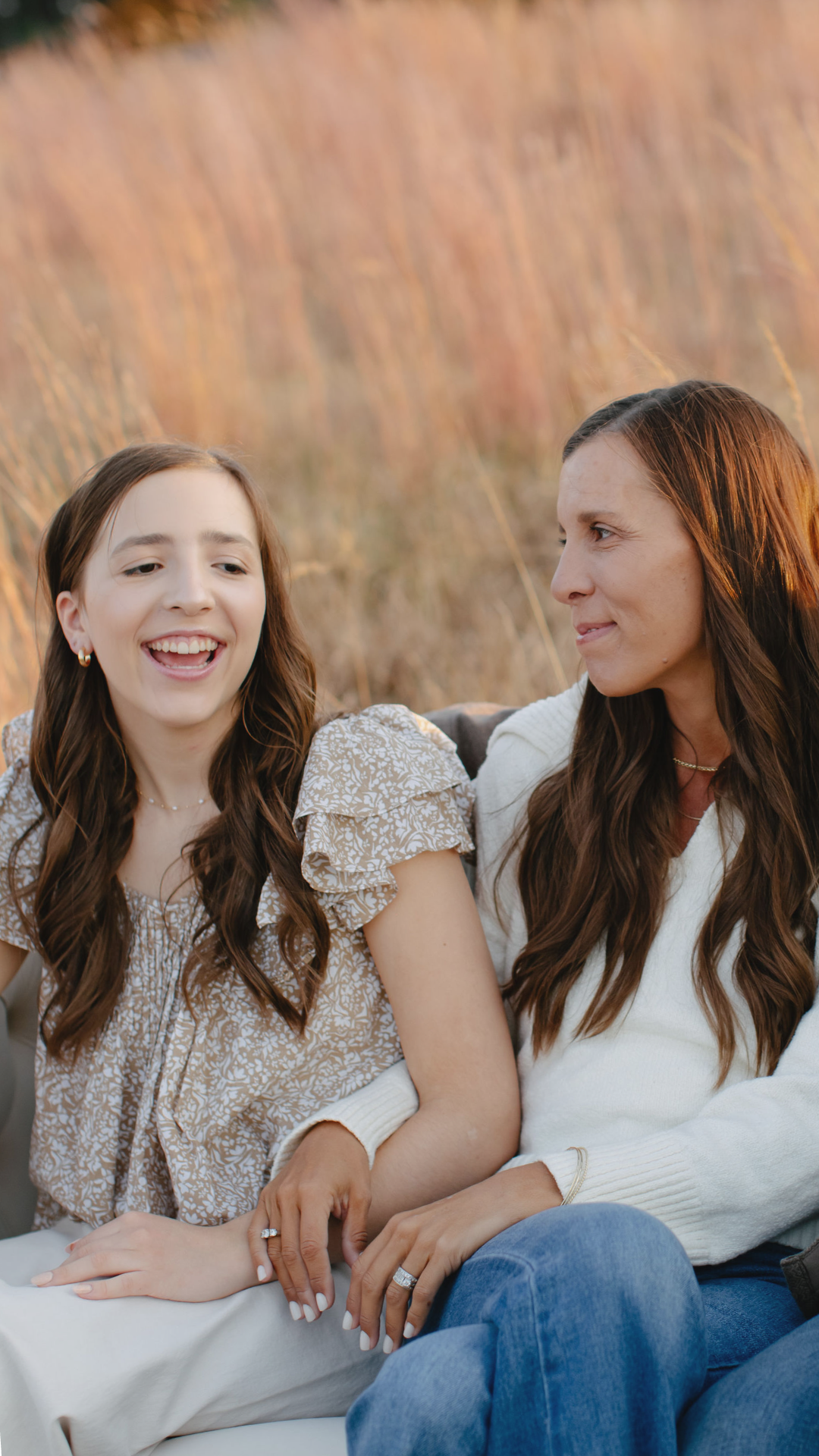 Amy looking at daughter and both smiling in a field of grass