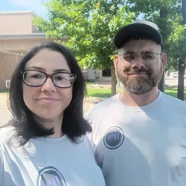 A man and a woman are standing next to each other in a park.