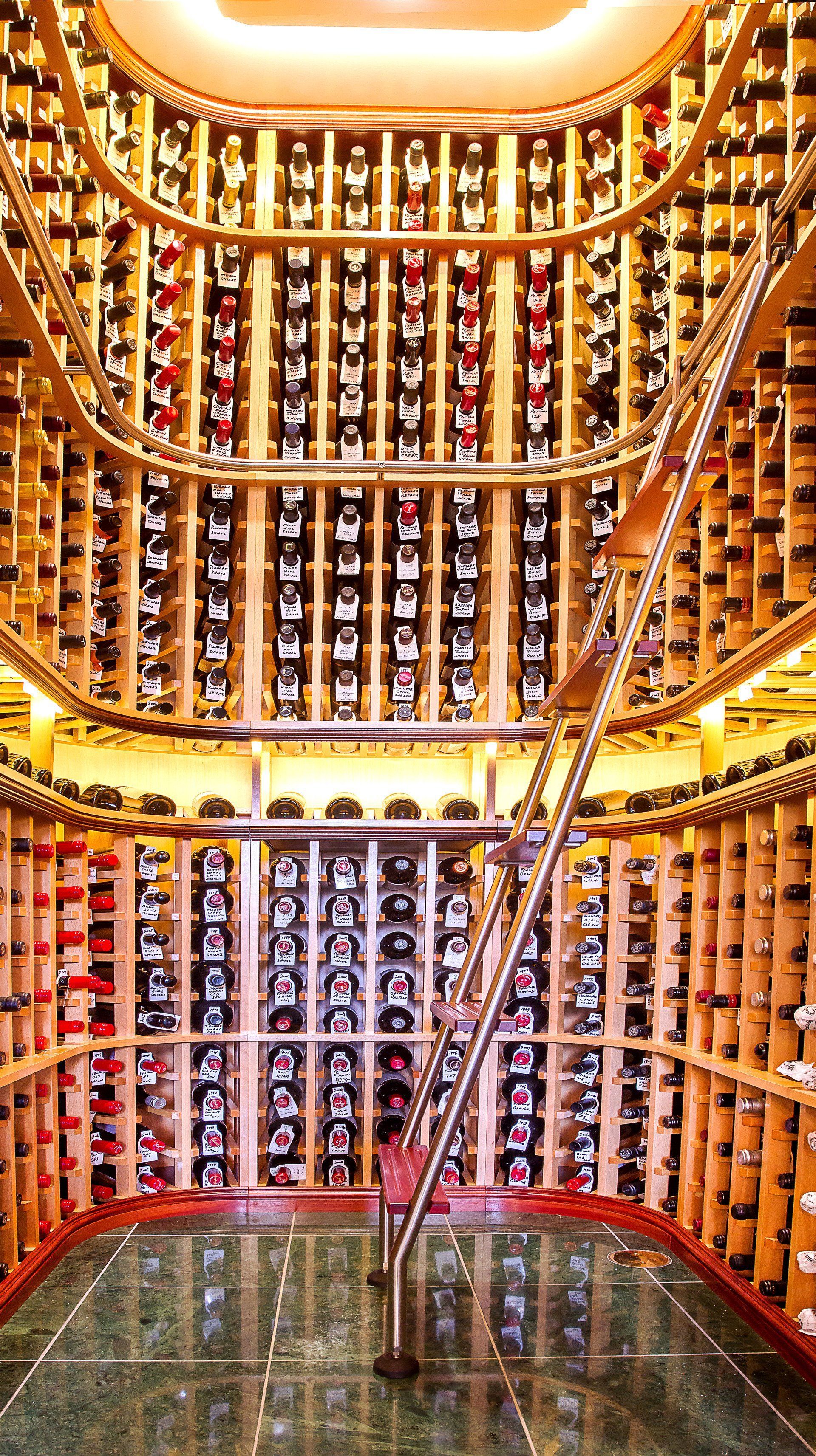A Woman Is Standing in A Large Wine Cellar Filled with Lots of Wine Bottles — Marlix Custom Timber Furniture Design and Joinery in Unanderra, NSW