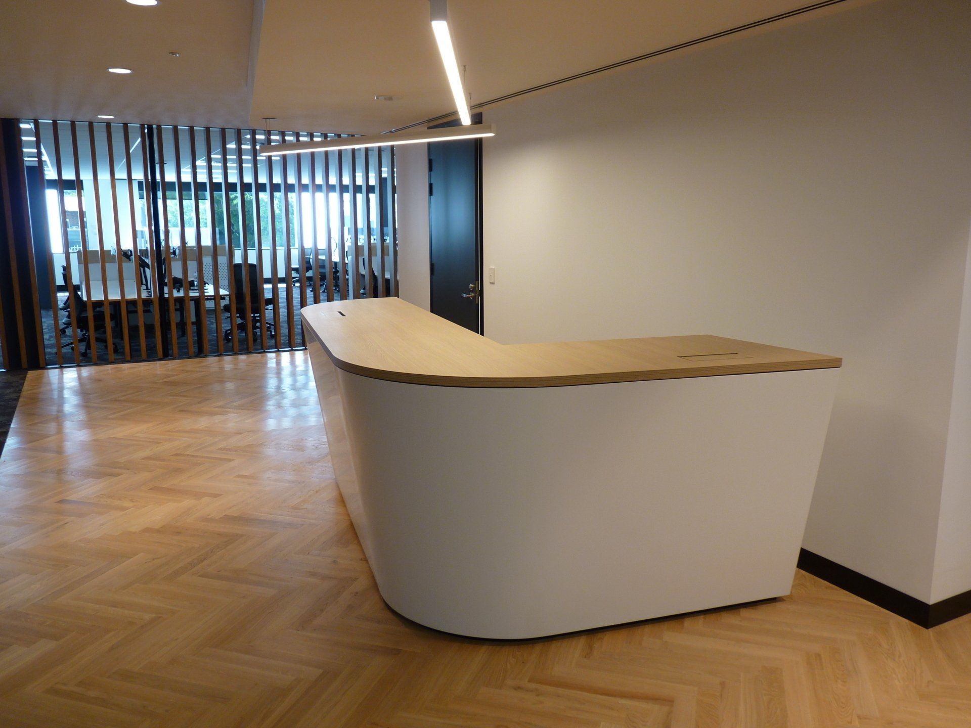 A White Reception Desk with A Wooden Top Is in A Room with A Wooden Floor — Marlix Custom Timber Furniture Design and Joinery in Unanderra, NSW