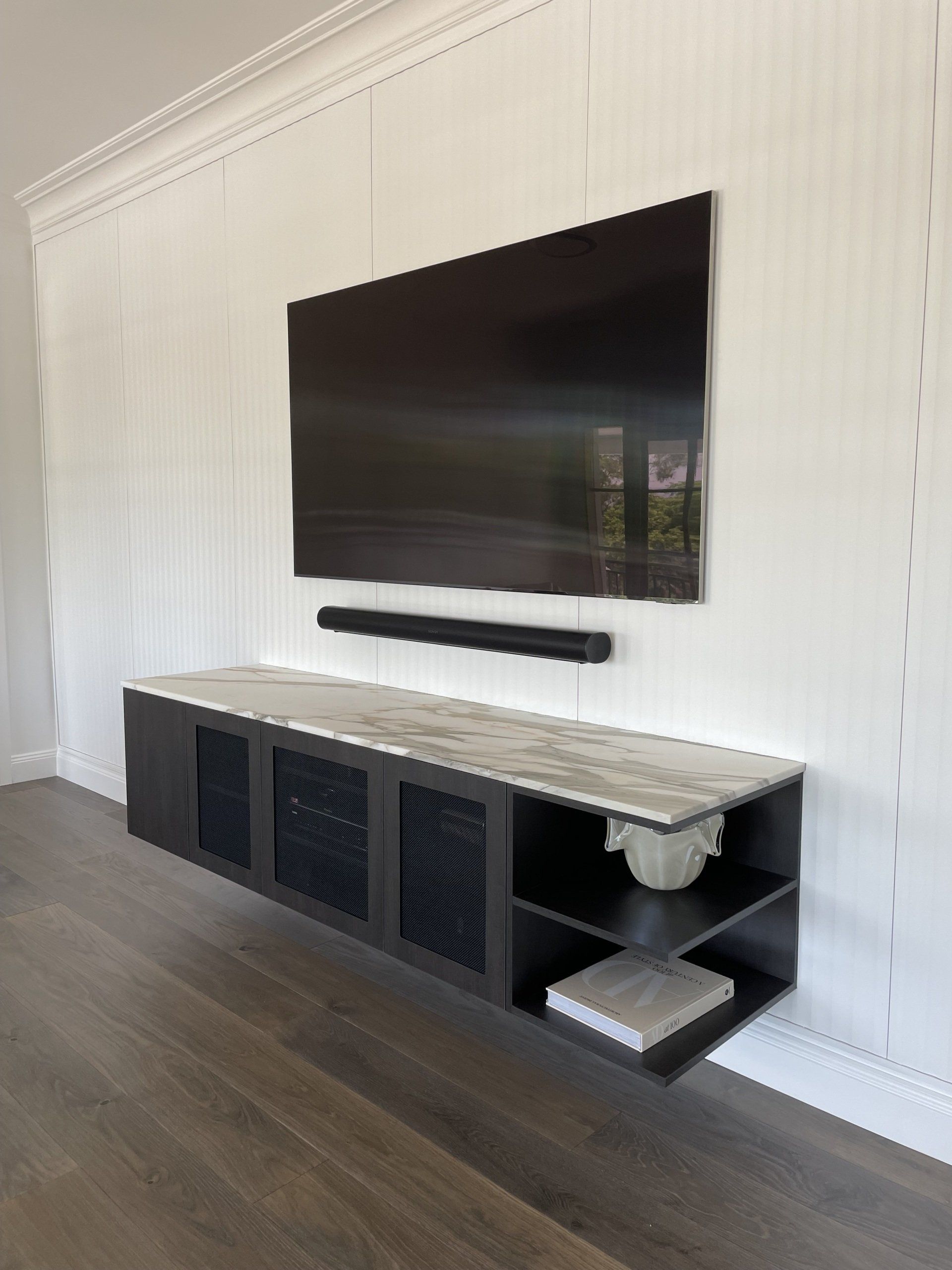 A Large Flat Screen Tv Is Mounted to The Wall Above a Marble Entertainment Center — Marlix Custom Timber Furniture Design and Joinery in Unanderra, NSW