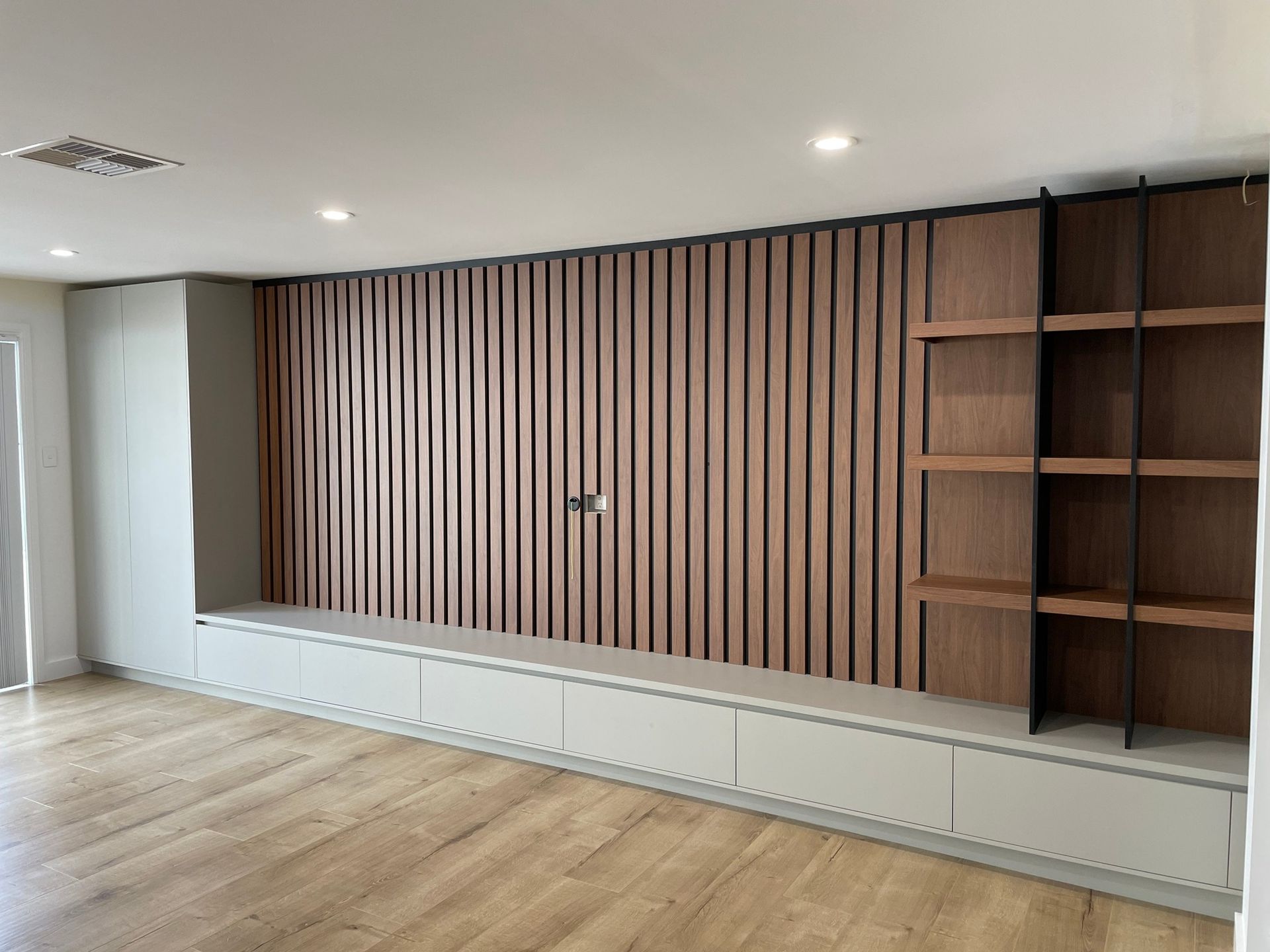 A Living Room with A Wooden Wall and Shelves — Marlix Custom Timber Furniture Design and Joinery in Unanderra, NSW