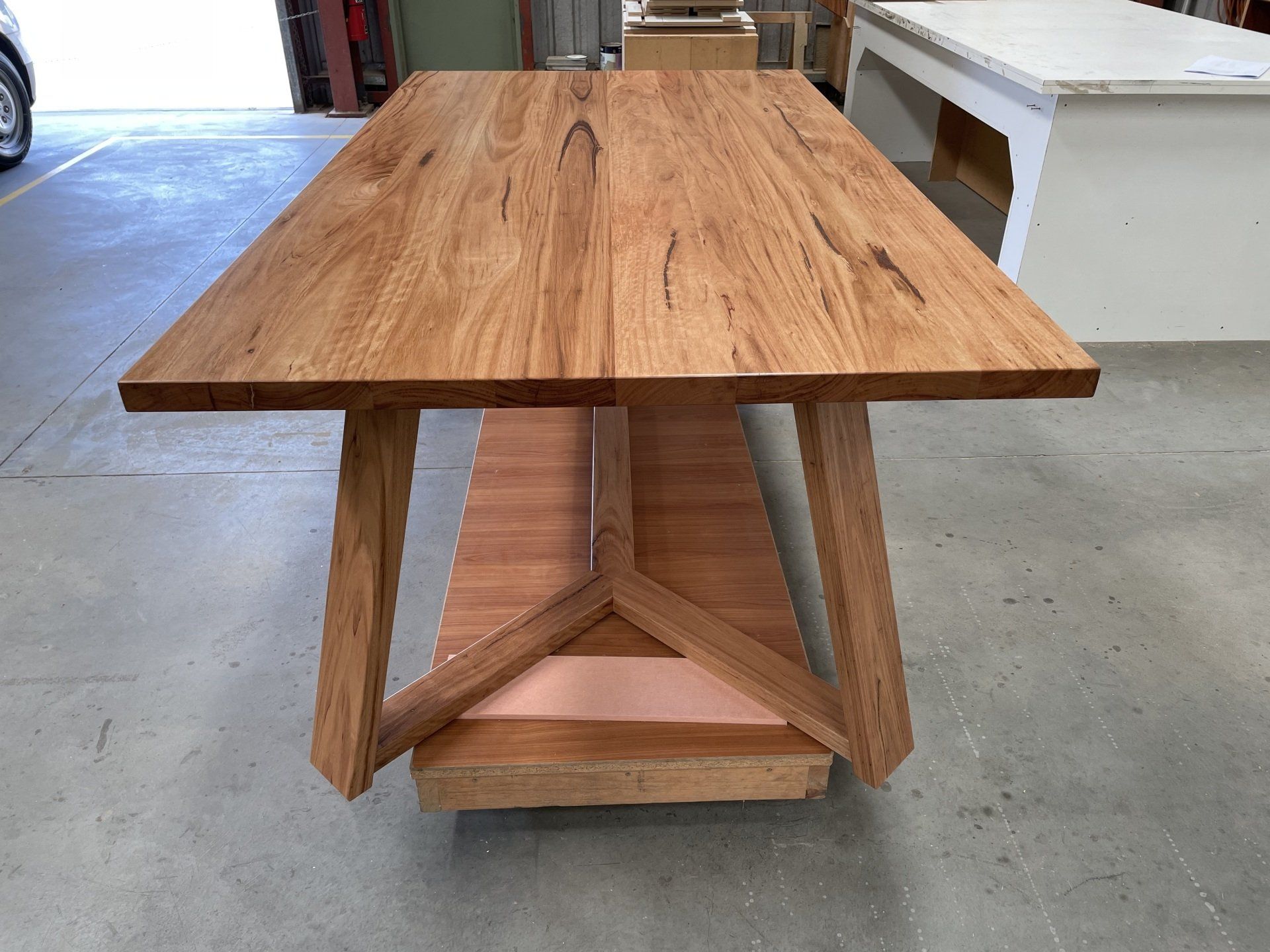 A Wooden Table Is Sitting On A Concrete Floor In A Garage — Marlix Custom Timber Furniture Design and Joinery in Unanderra, NSW