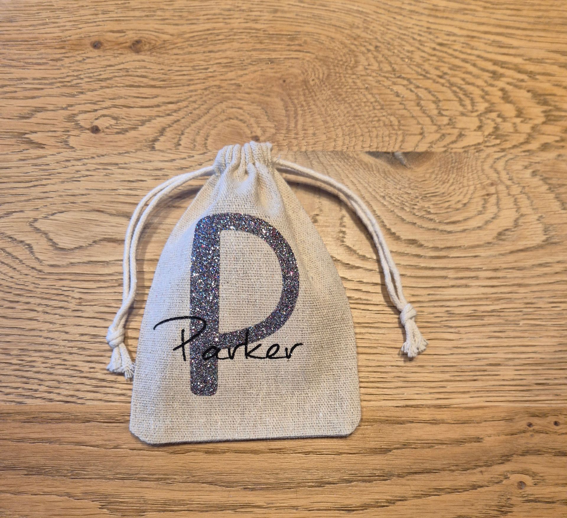 Beige tas met trekkoord, waarop de naam