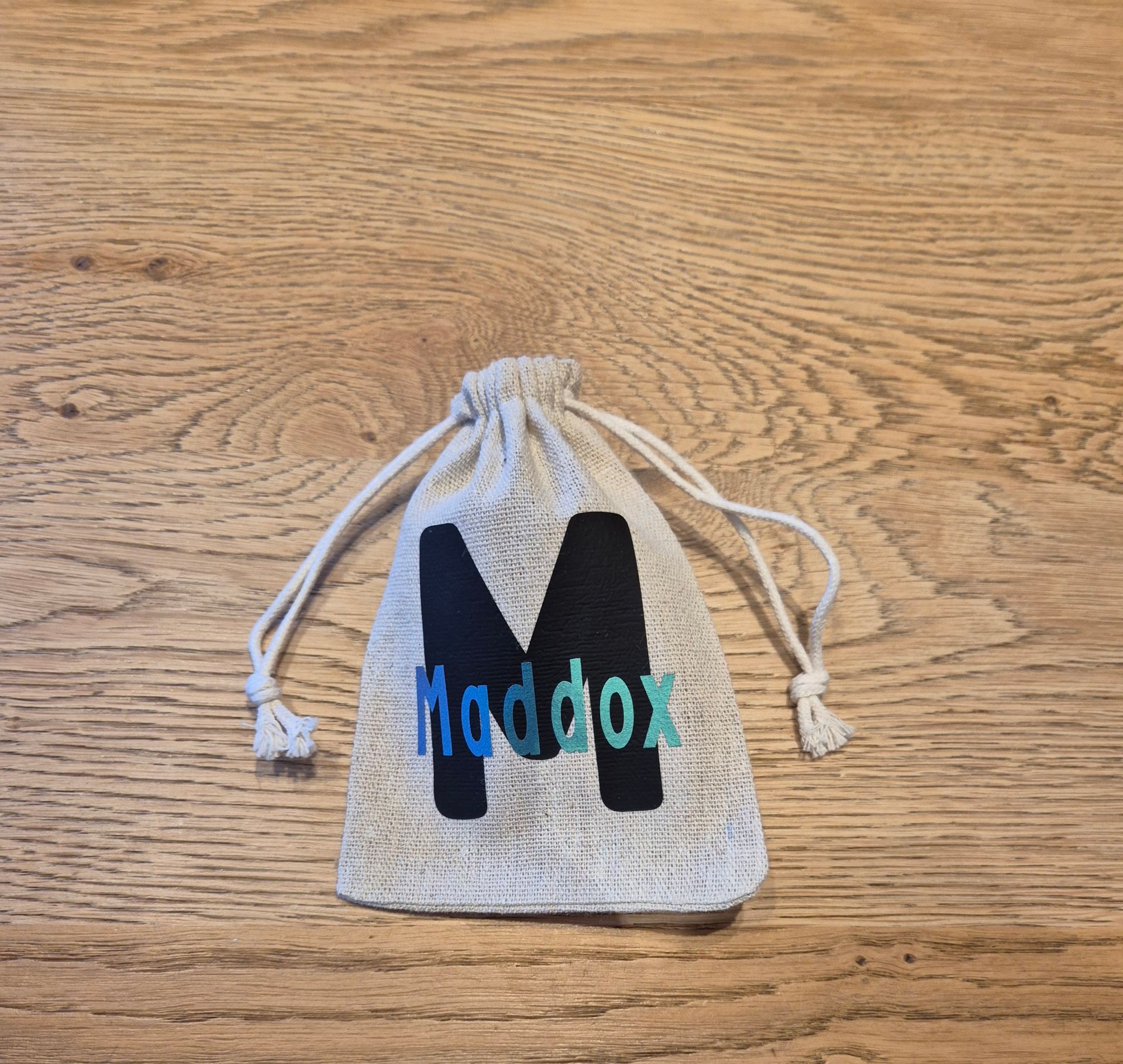 Beige tas met trekkoord, waarop de naam