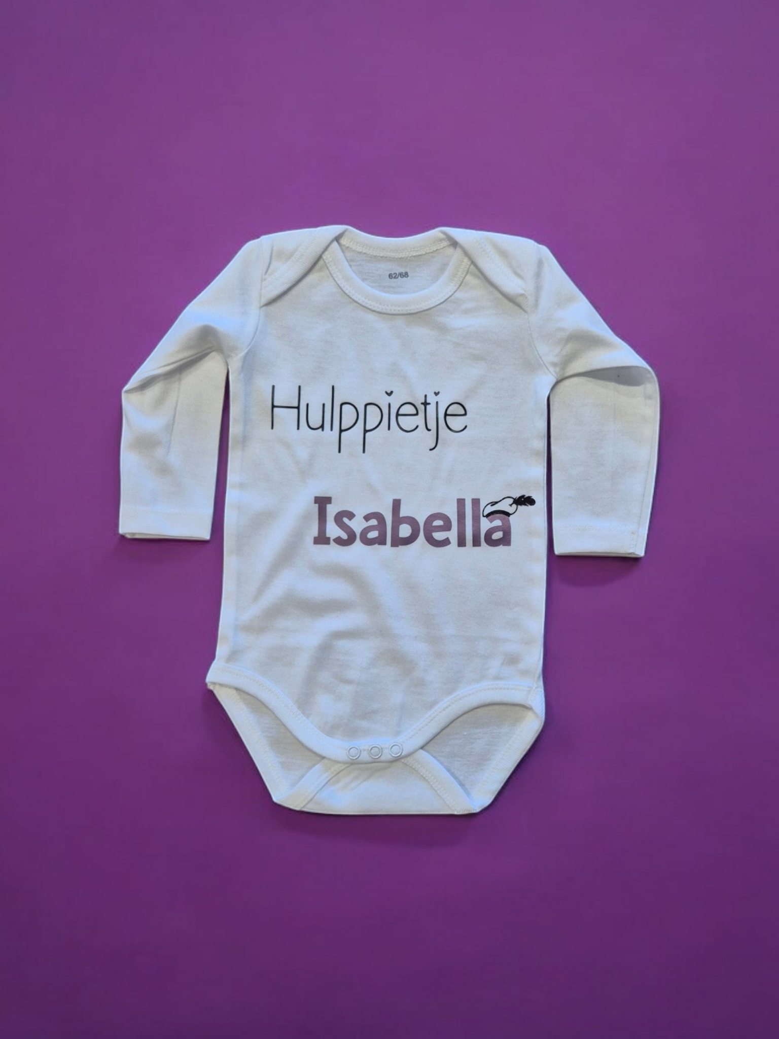Witte babyromper met de naam "Isabella" en de tekst "Hulppietje" op een paarse achtergrond.
