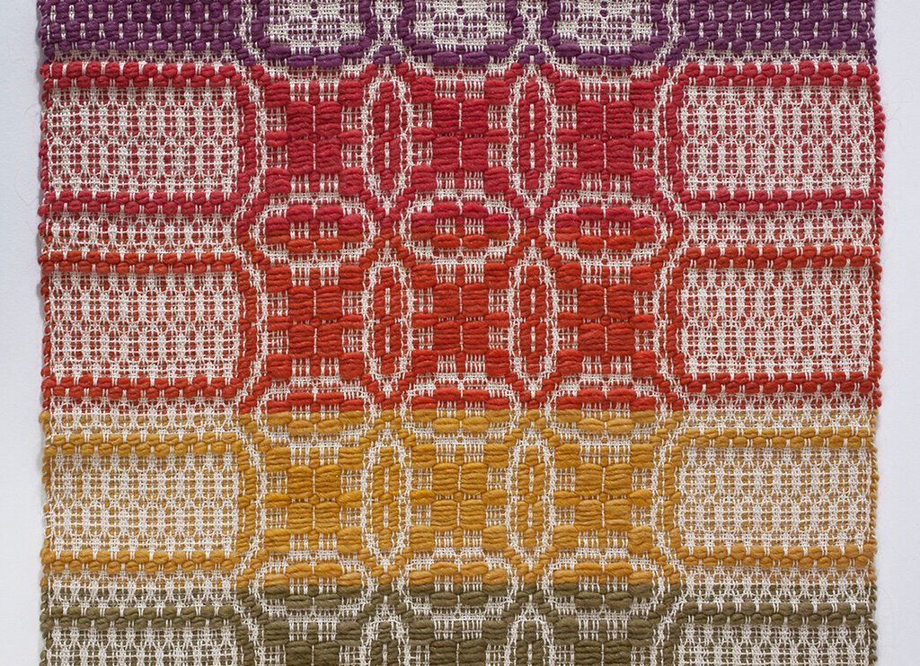 A close up of a colorful weaving with a rainbow pattern on it.