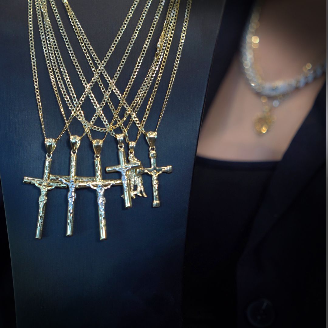 Gold crucifix necklaces on a display and a diamond necklace on a person.