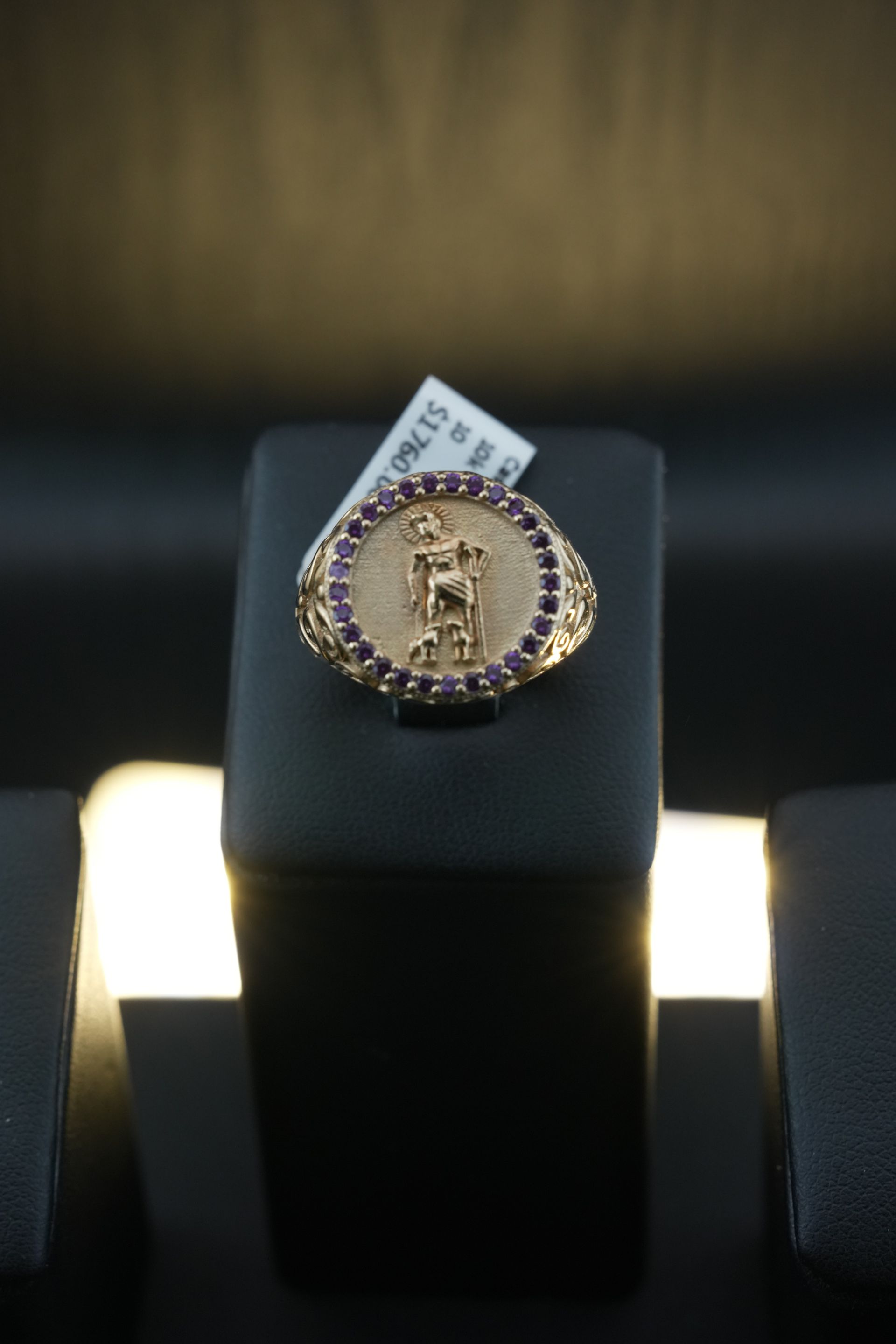 Gold ring with a central figure, surrounded by small red gems.