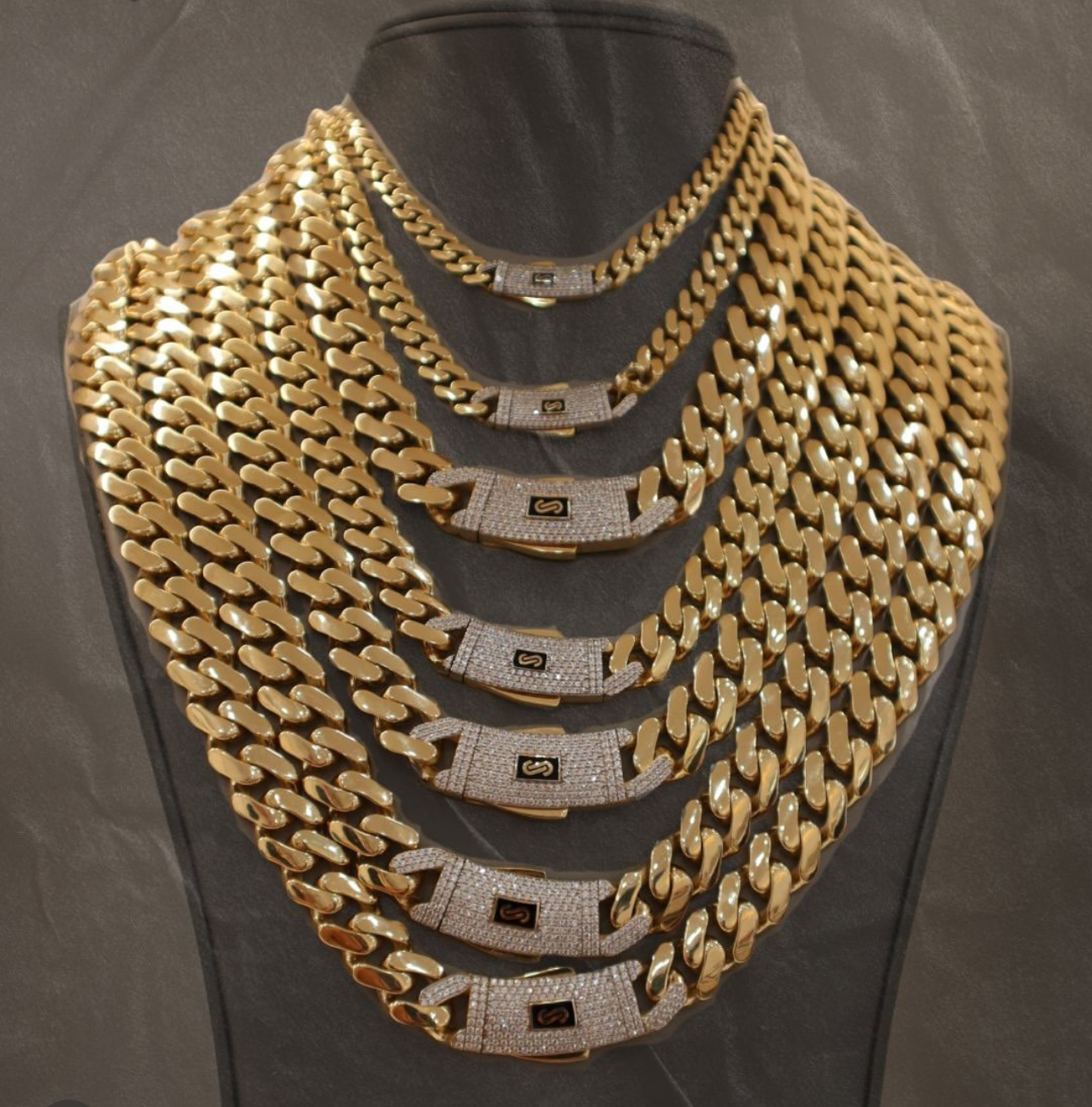 Gold chain necklaces of various sizes on display, with diamond-studded clasps.