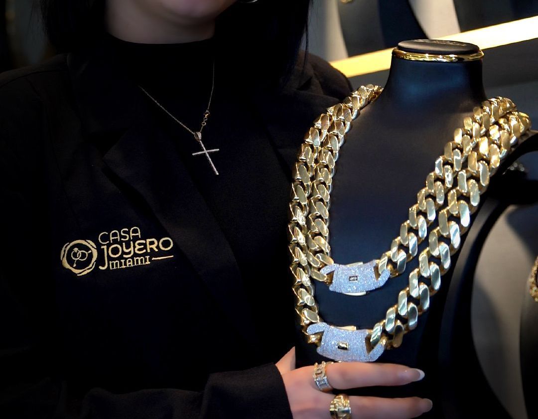 Woman holding gold jewelry chains on display in a store.