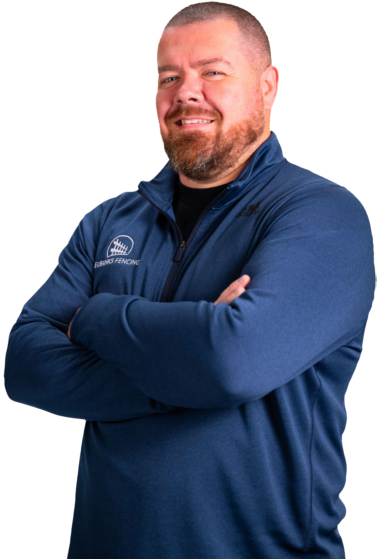 A person with a beard, wearing a blue quarter-zip pullover with a logo, smiling with arms crossed against a white background.