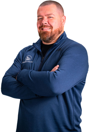 A person with a beard, wearing a blue quarter-zip pullover with a logo, smiling with arms crossed against a white background.