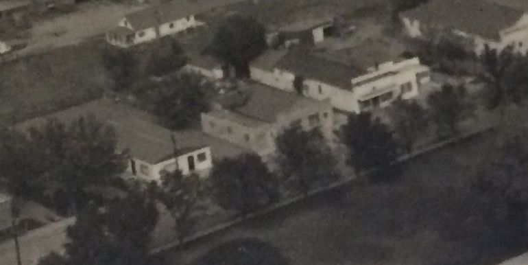 An aerial view of a house surrounded by trees in a black and white photo.