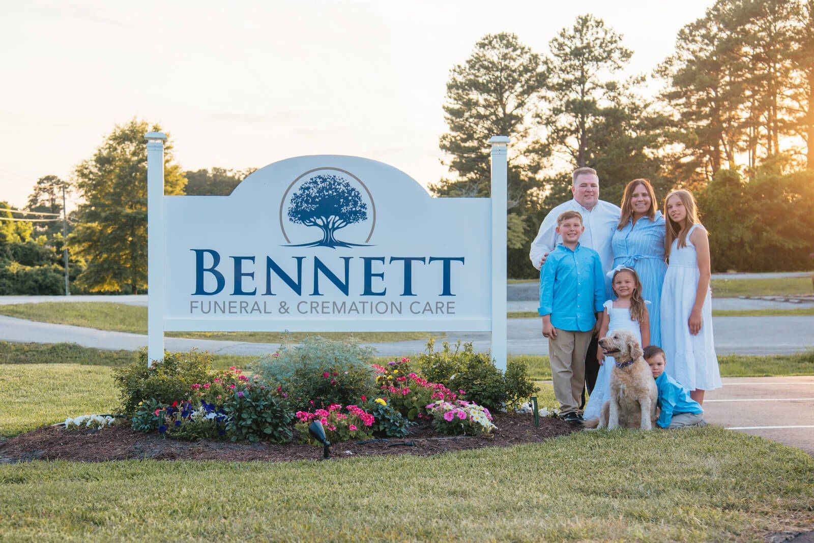 Bennett Memorial & Cremation Care sign with a family standing beside it at sunset