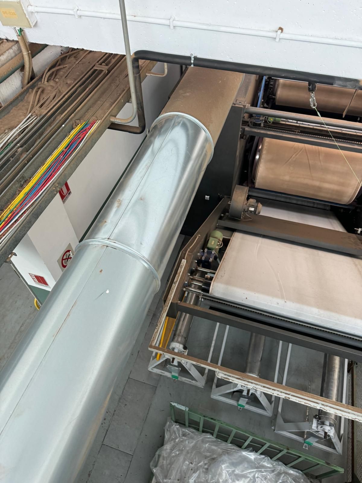 Soffitto industriale con grandi condotti argentati e macchinari per il trasporto in un ambiente di fabbrica