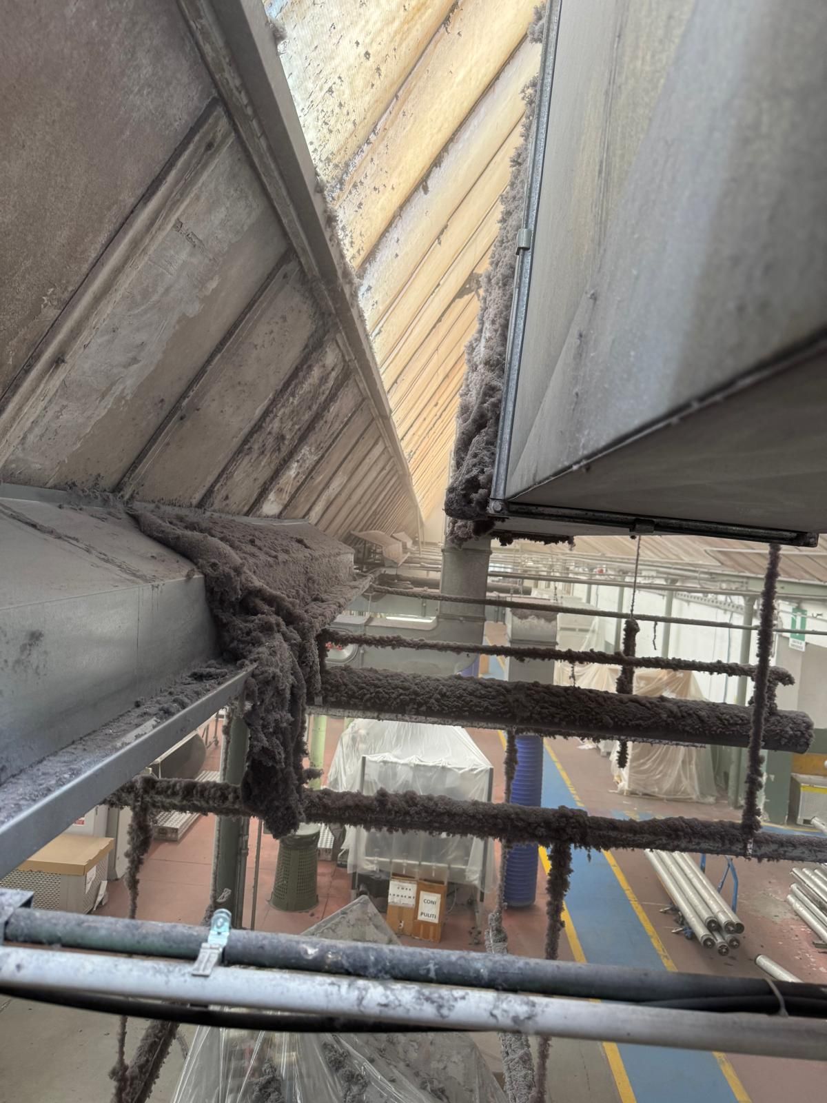 Ponteggio sotto un tetto danneggiato, con travi a vista e detriti in un cantiere edile