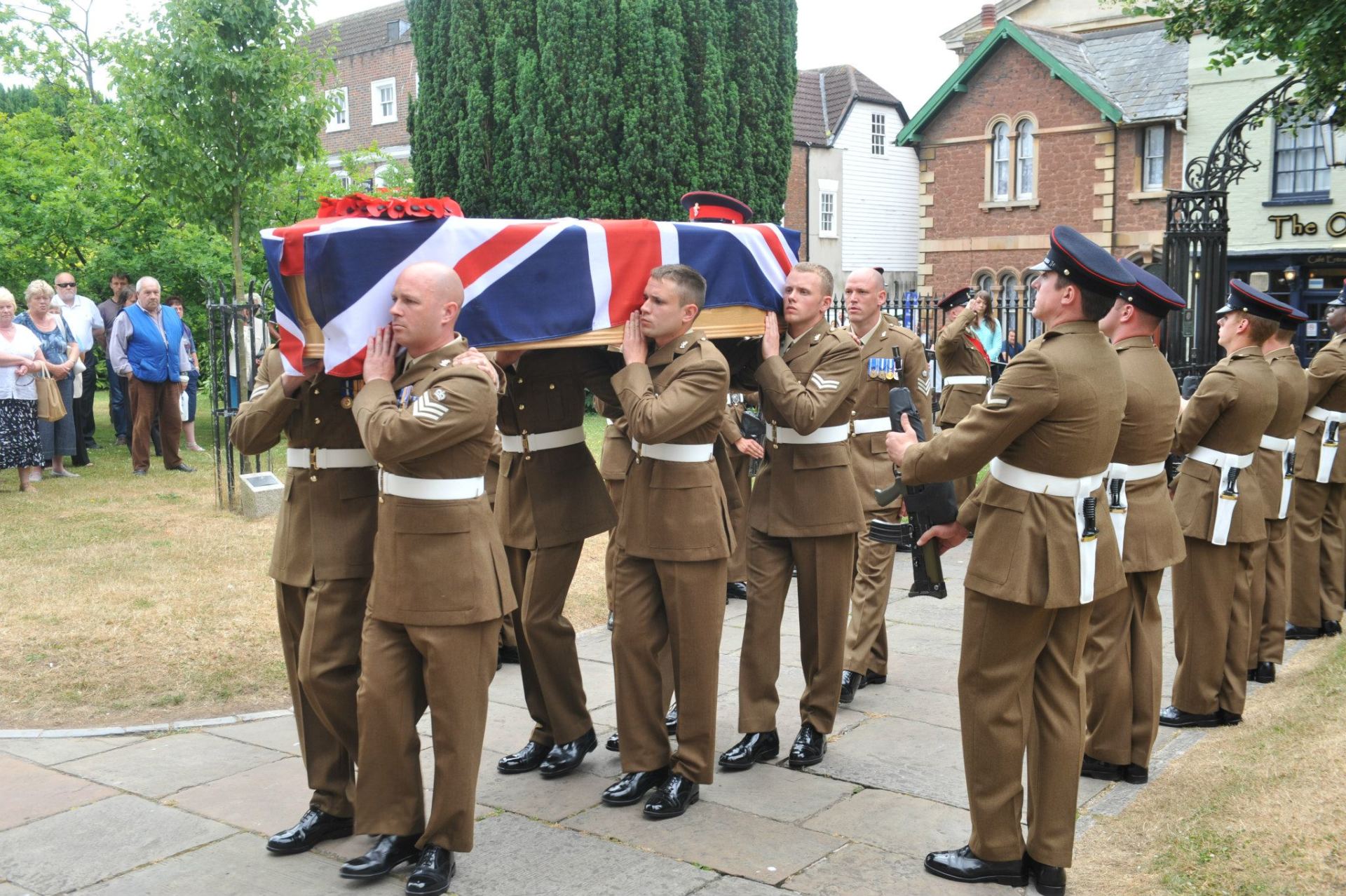 Soldiers carrying a flag draped coffin at a military funeral