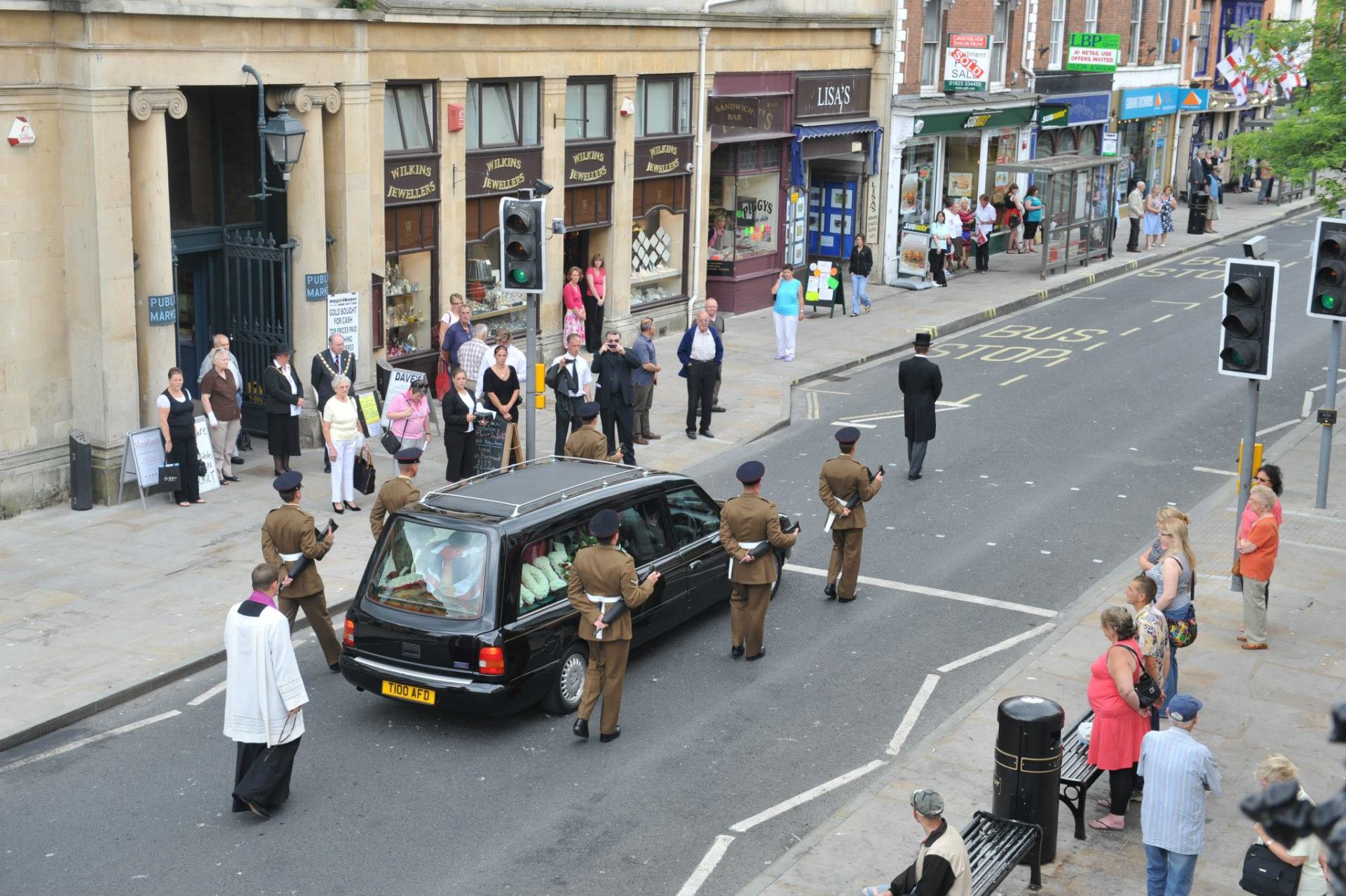 Military funeral procession moving through a town street