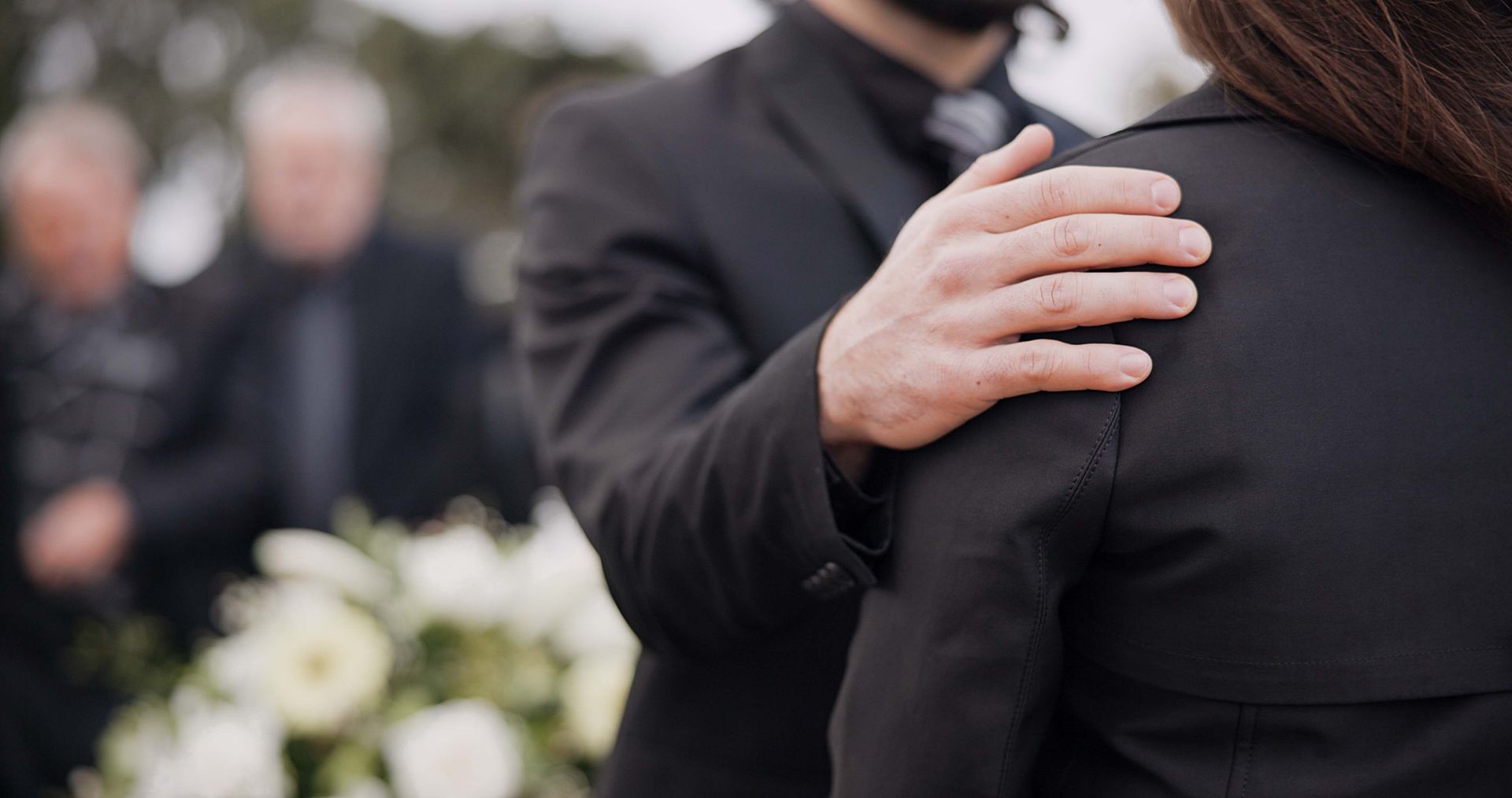 One person comforting another at a funeral