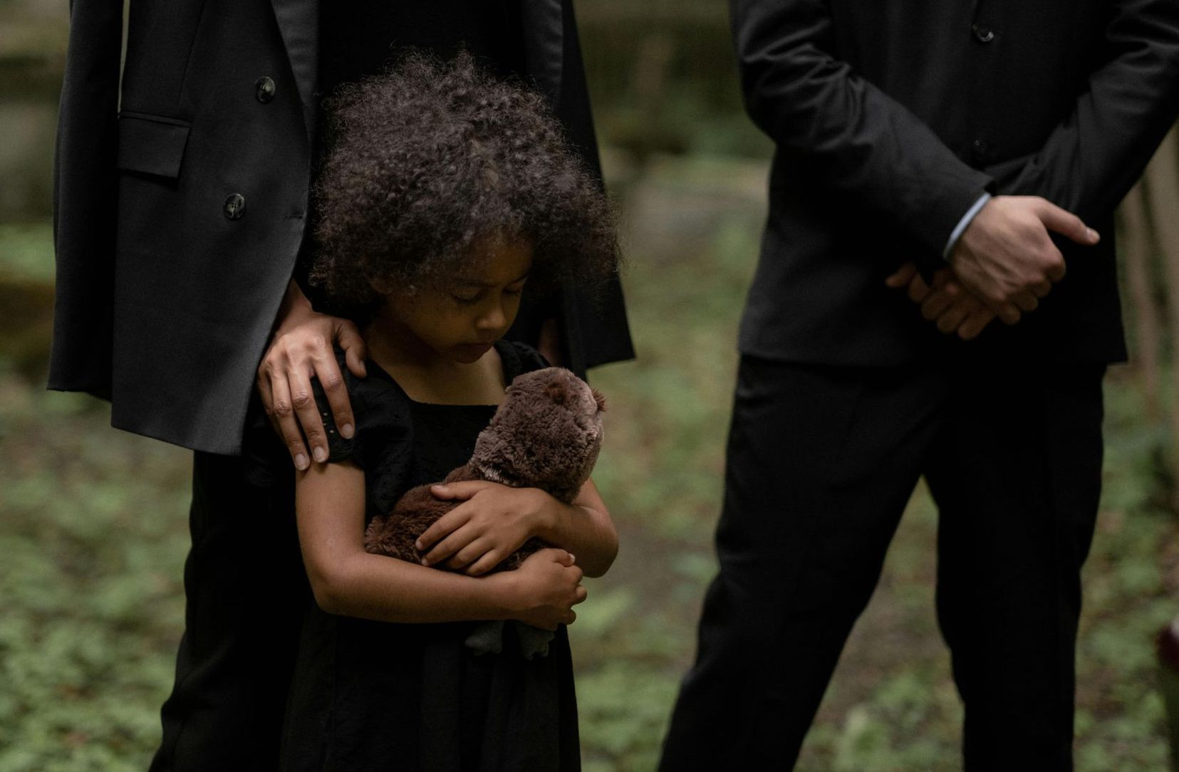 Little girl holding a stuffed toy at a funeral