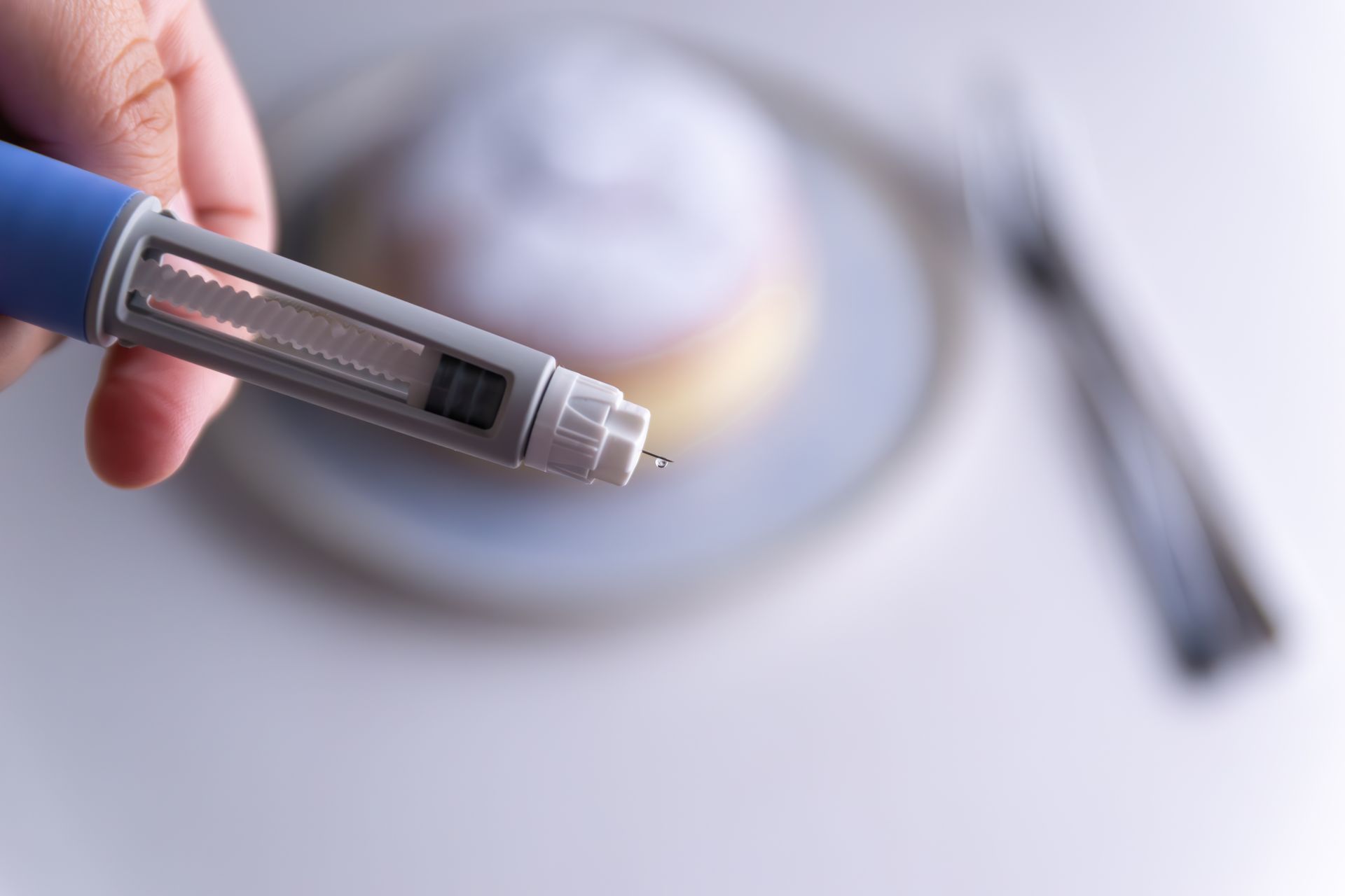 Hand holding a test pen near a bowl on a white table with a knife in the background