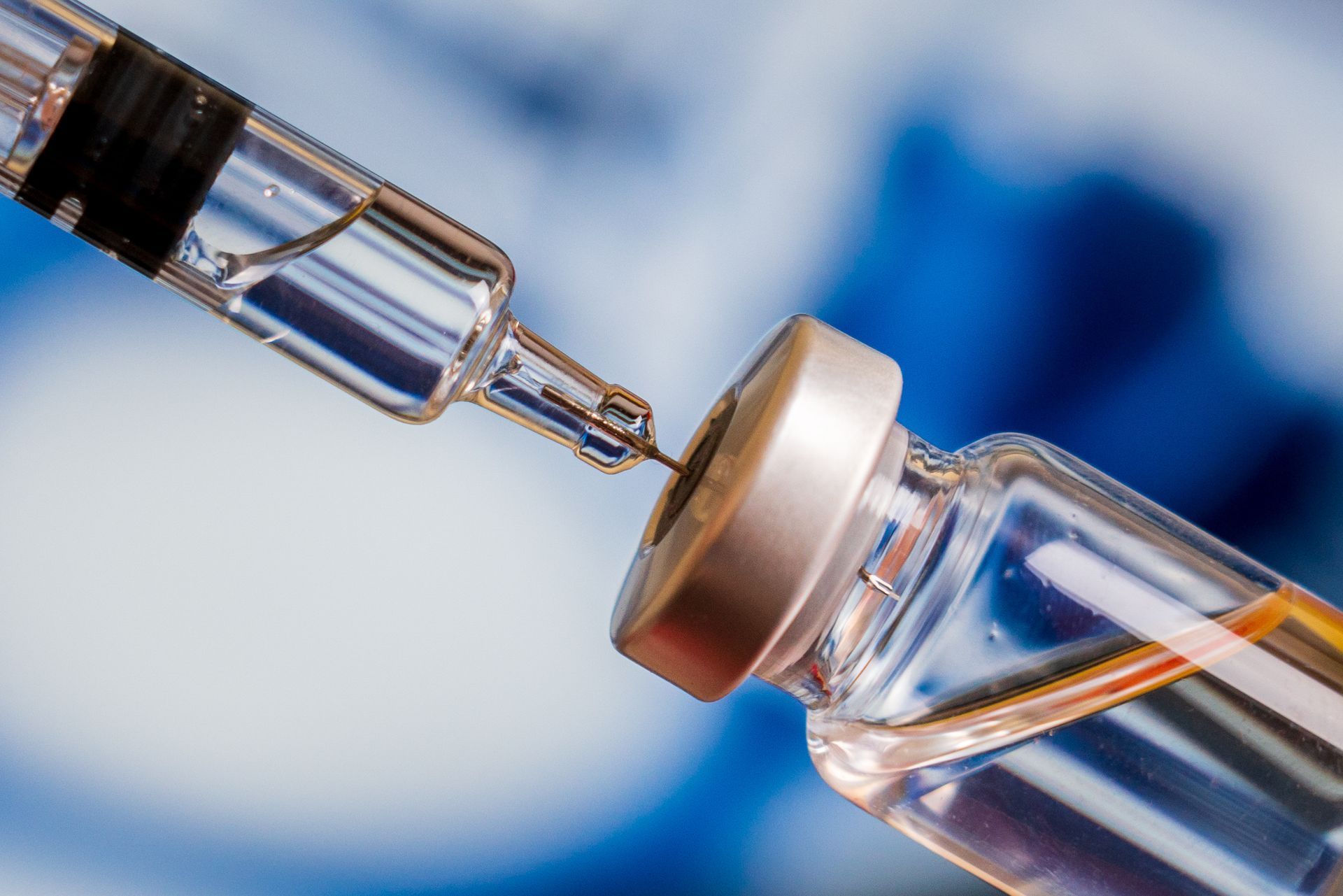 Close-up of a syringe needle drawing liquid from a vaccine vial Close-up of a syringe needle drawing liquid from a vaccine vial