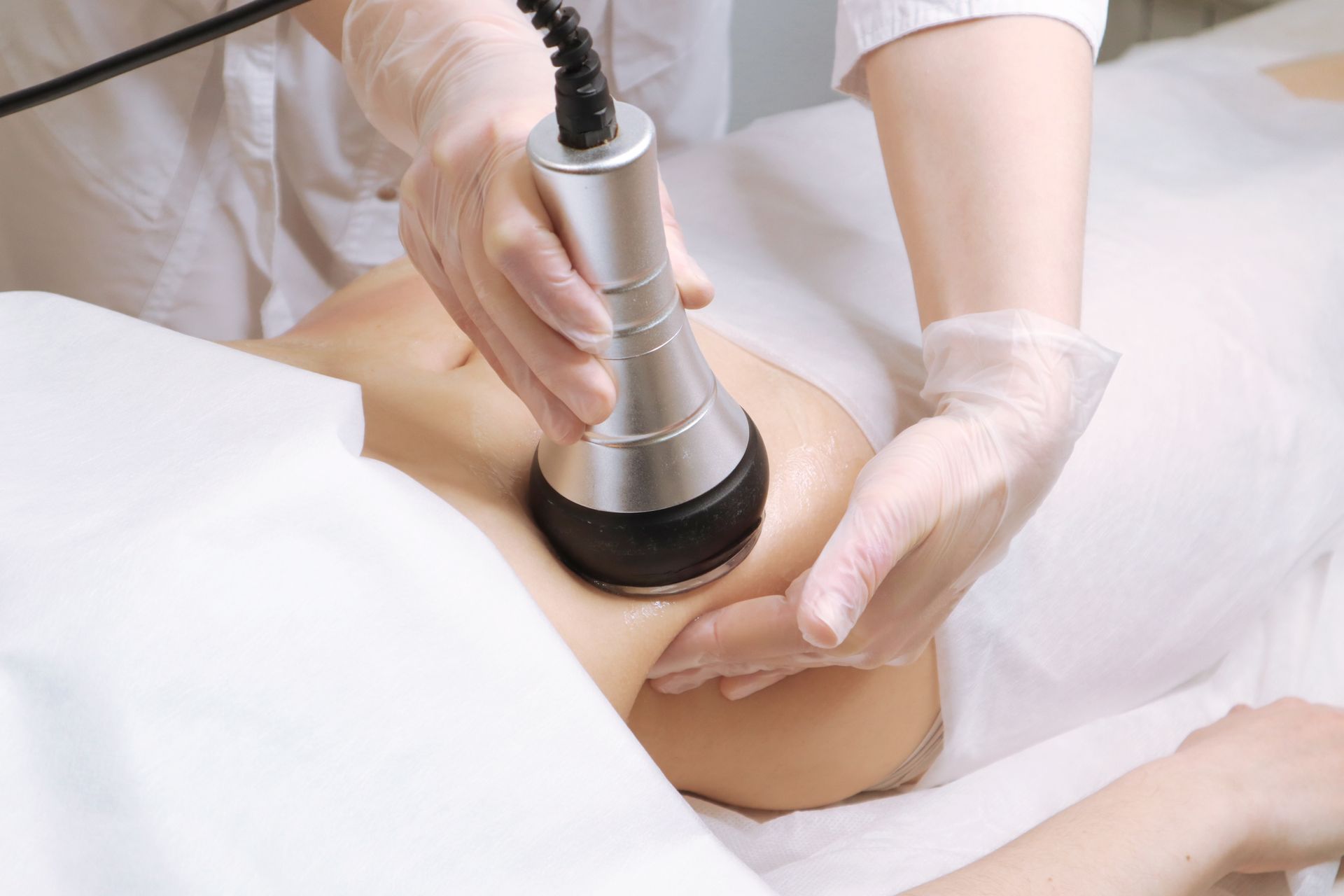 Gloved hands using a handheld device on a person’s abdomen in a clinical setting