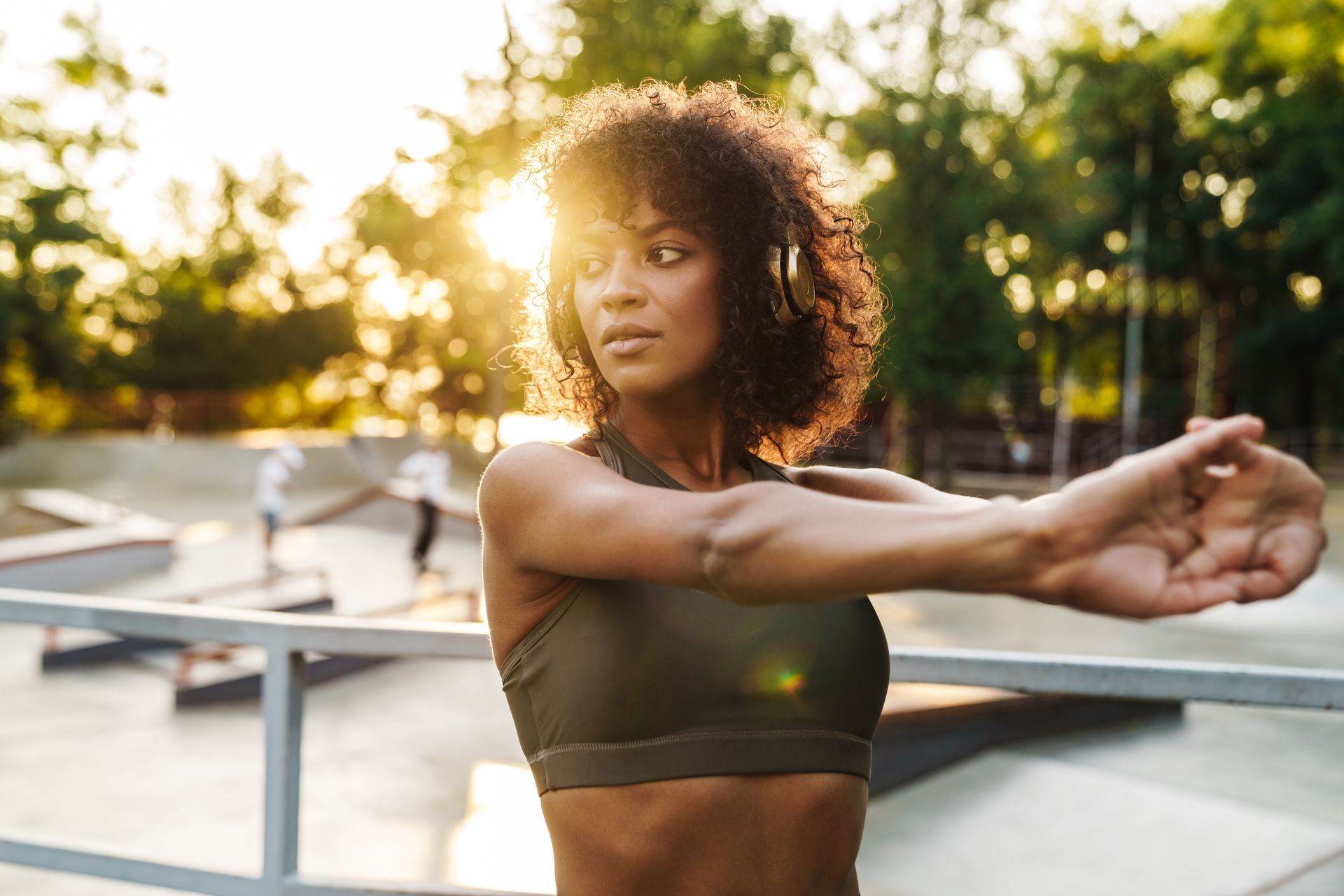 Person stretching outdoors at sunset in a park, wearing a dark sports top. Person stretching outdoors at sunset in a park, wearing a dark sports top.